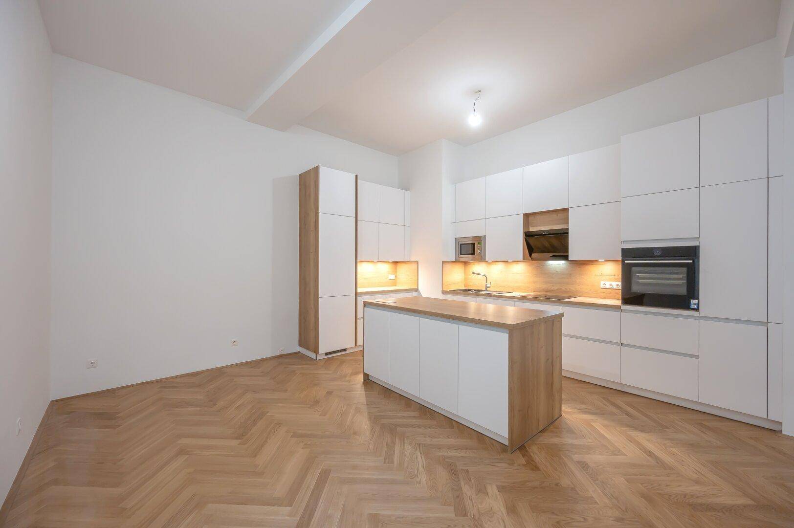 Geräumige, moderne Küche mit Kochinsel, weißen Schränken und Holzelementen.