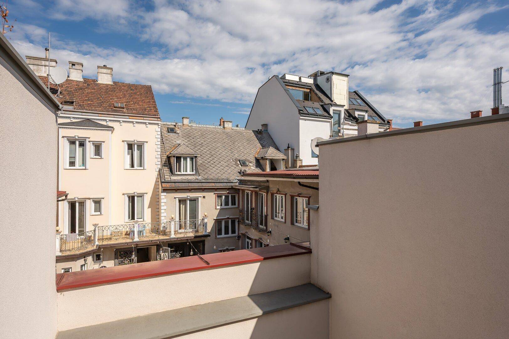 Dachterrasse mit Blick auf die umliegenden Gebäude und den blauen Himmel.