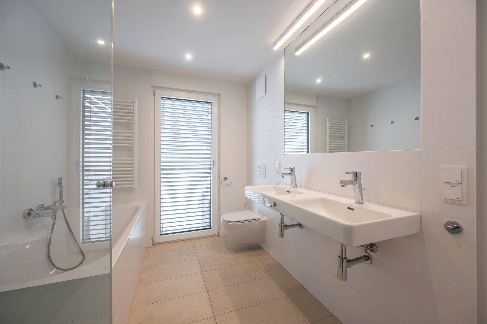 Modernes Badezimmer mit Doppelwaschbecken, Badewanne, Dusche und Fenster.