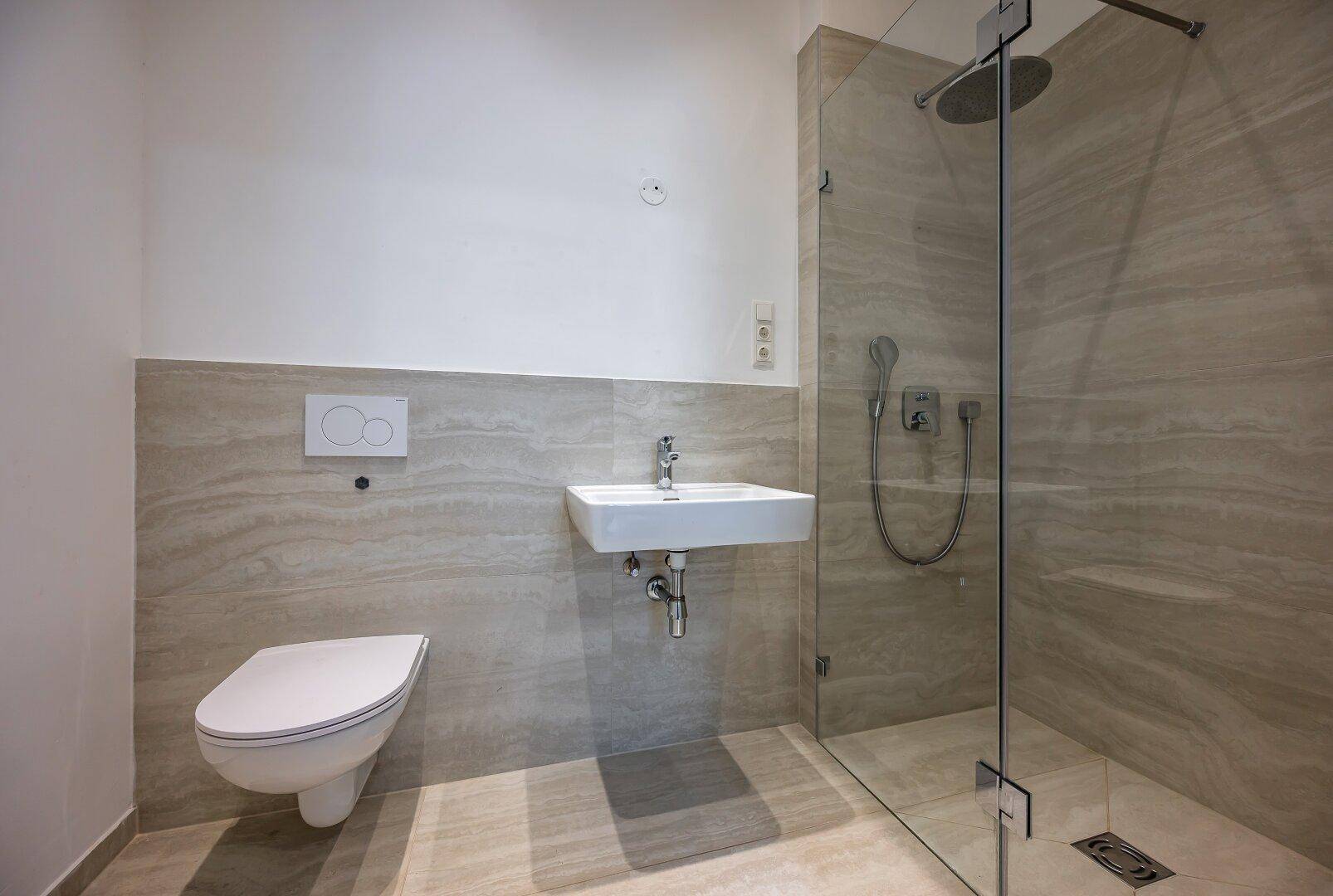 Modernes Badezimmer mit ebenerdiger Dusche, wandhängendem WC und Waschbecken.