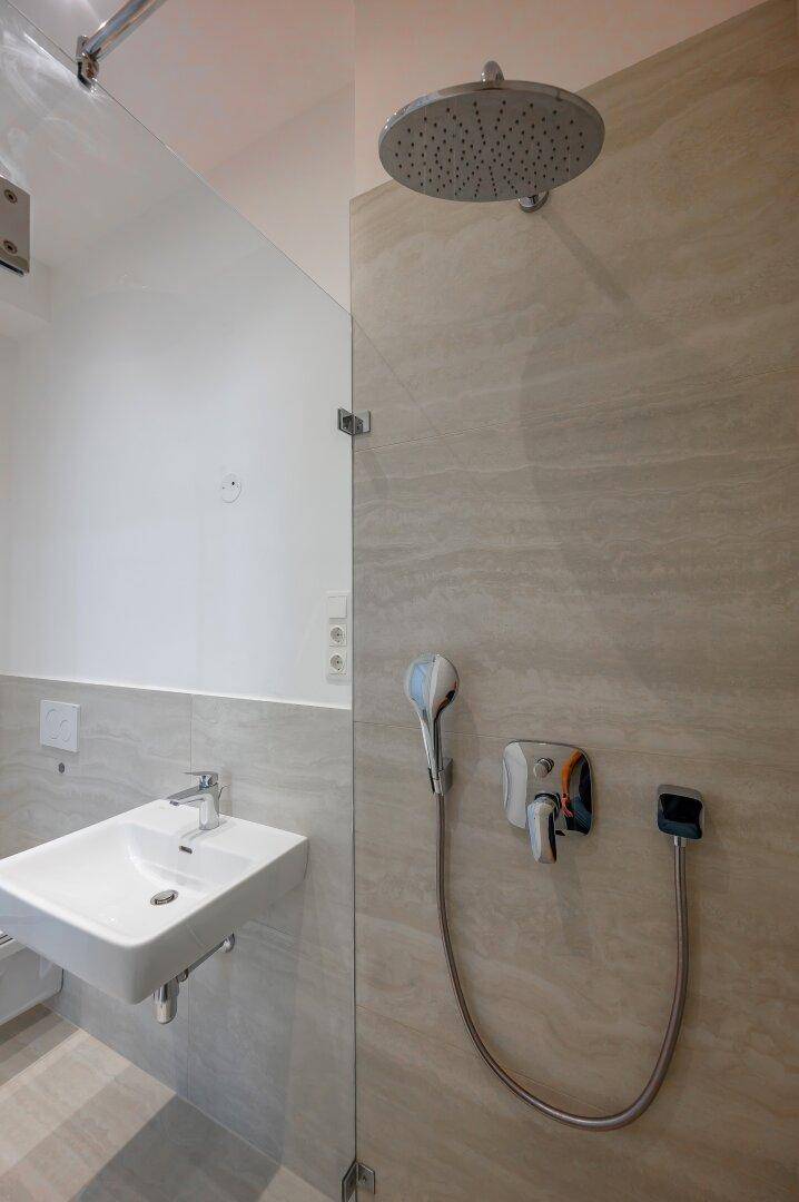 Detailansicht der Regendusche und des modernen Waschbeckens im Badezimmer.
