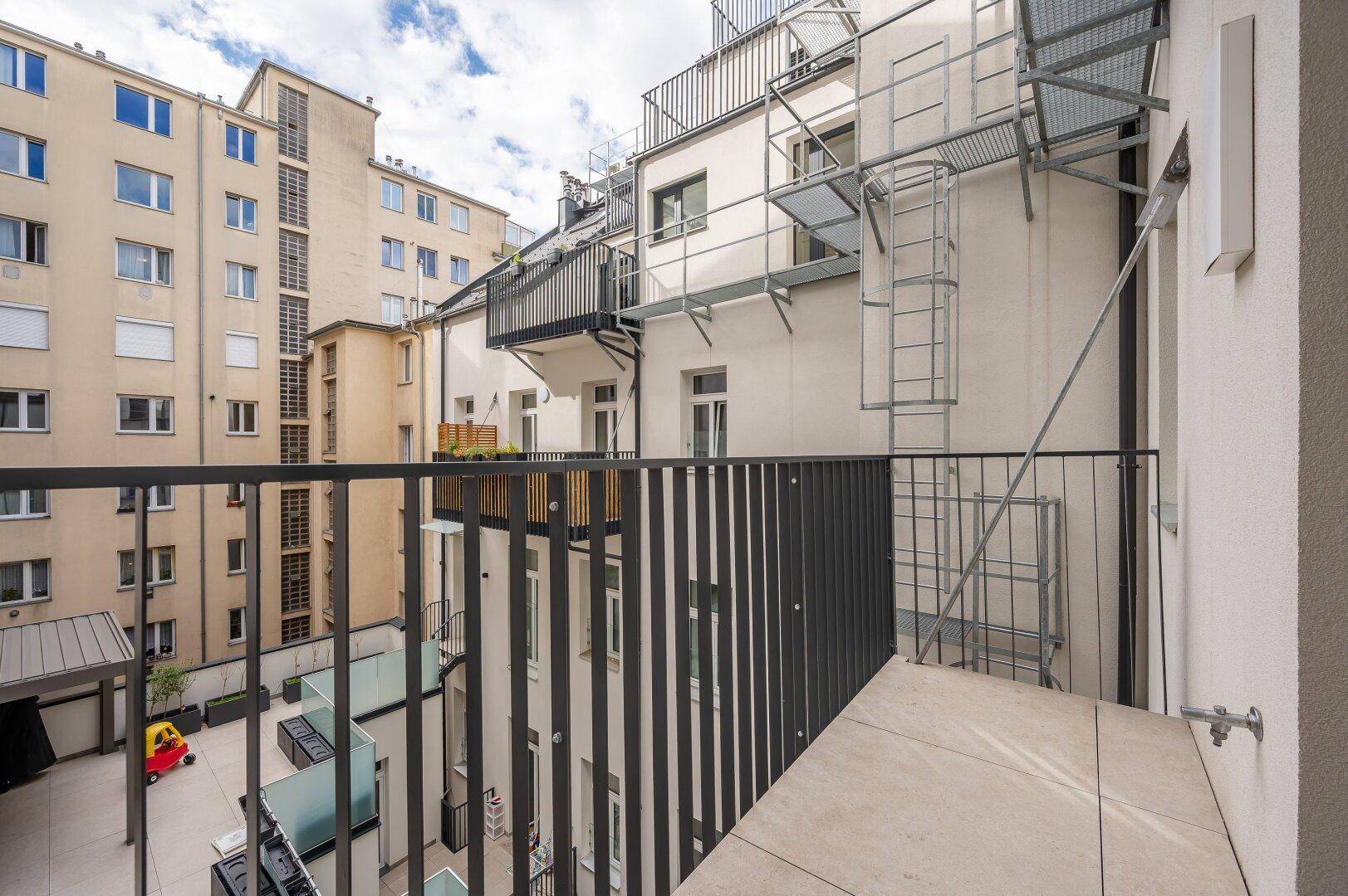 Balkon mit Blick auf den ruhigen Innenhof und die umliegenden Gebäude.