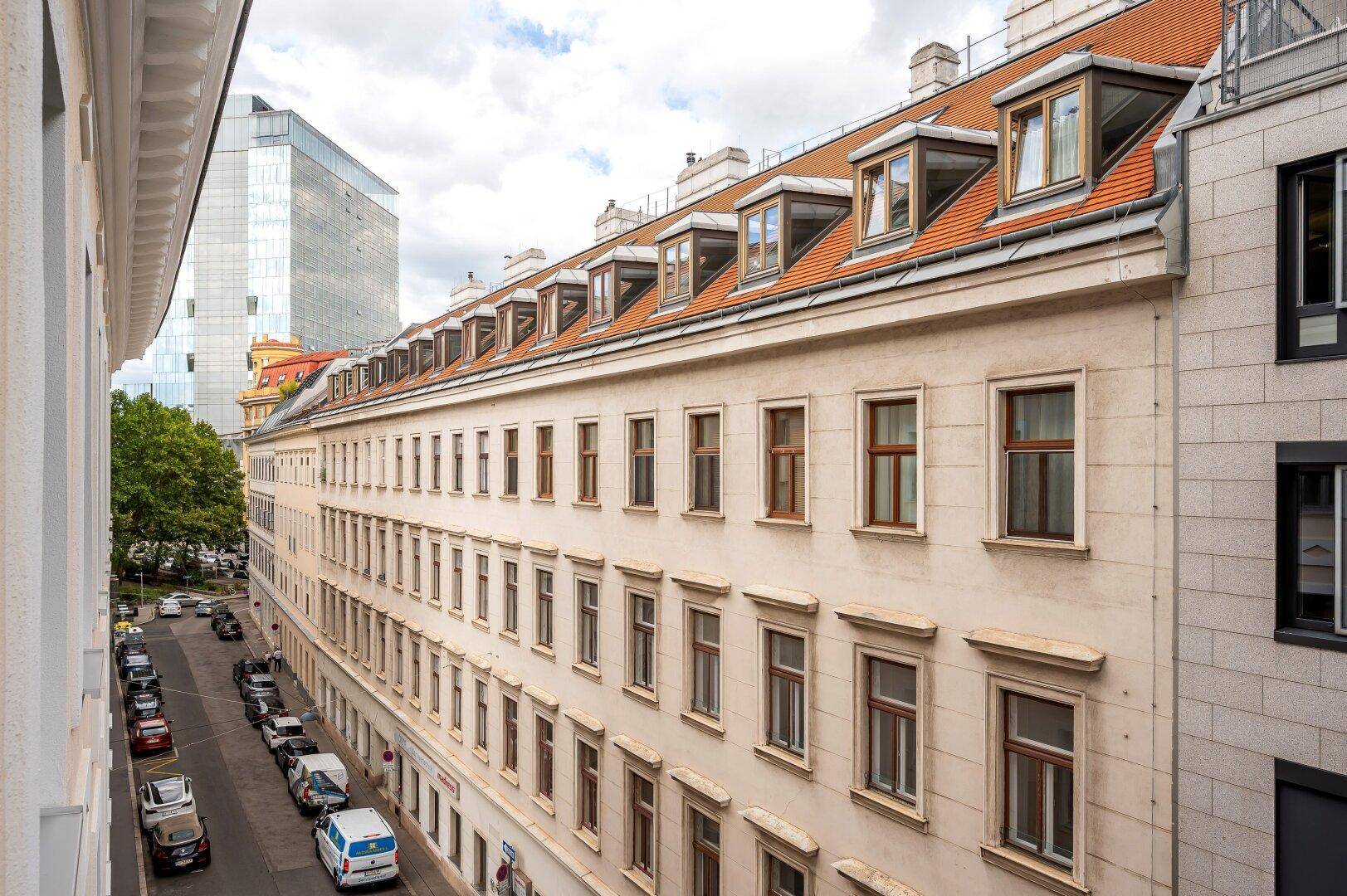 Traditionelles Gebäude mit Mansarddach und Blick auf die belebte Stadtstraße.