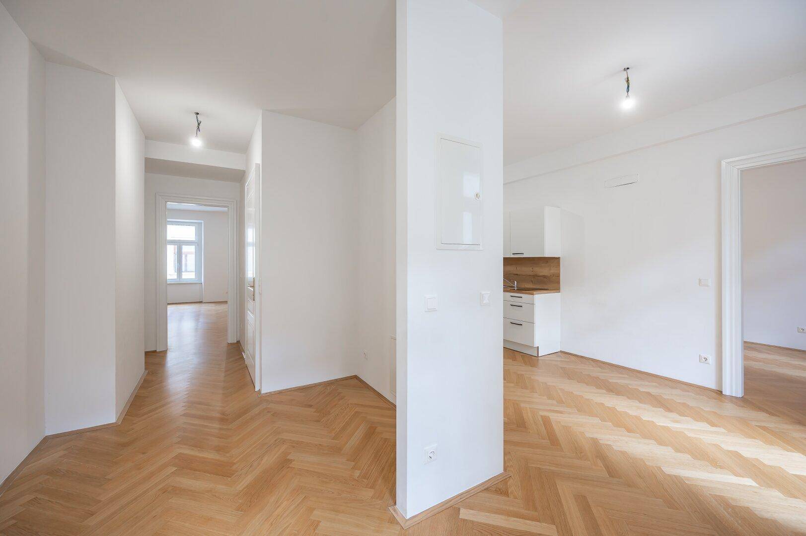 Geräumiger Flur mit Fischgrätparkett, der zu verschiedenen Zimmern der Wohnung führt.