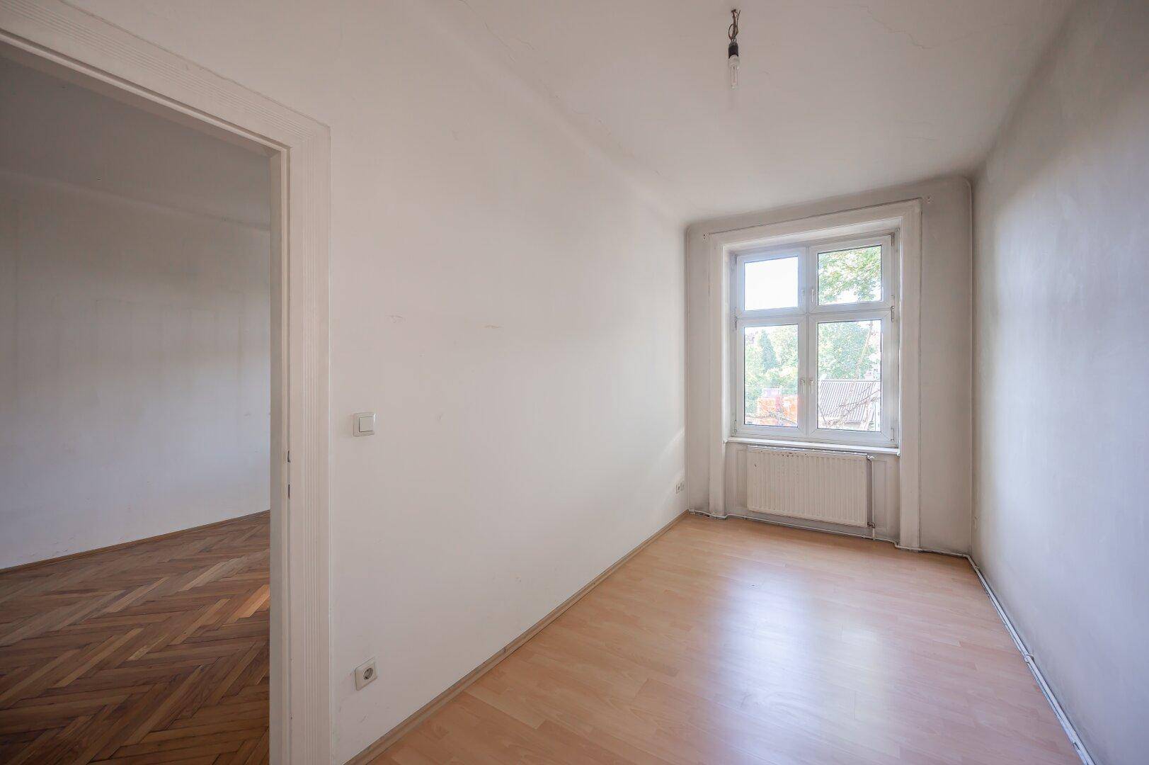 Helles Zimmer mit Laminatboden und einem Fenster, das den Raum gut belichtet.