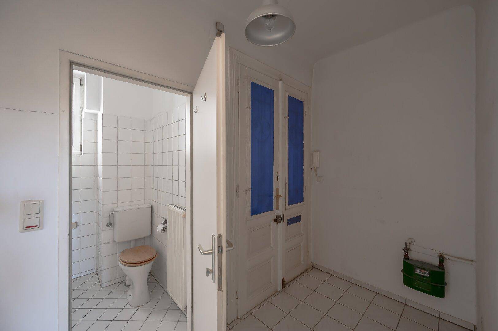 Separates WC mit Toilette und Fliesenboden, das eine einfache Ausstattung aufweist.
