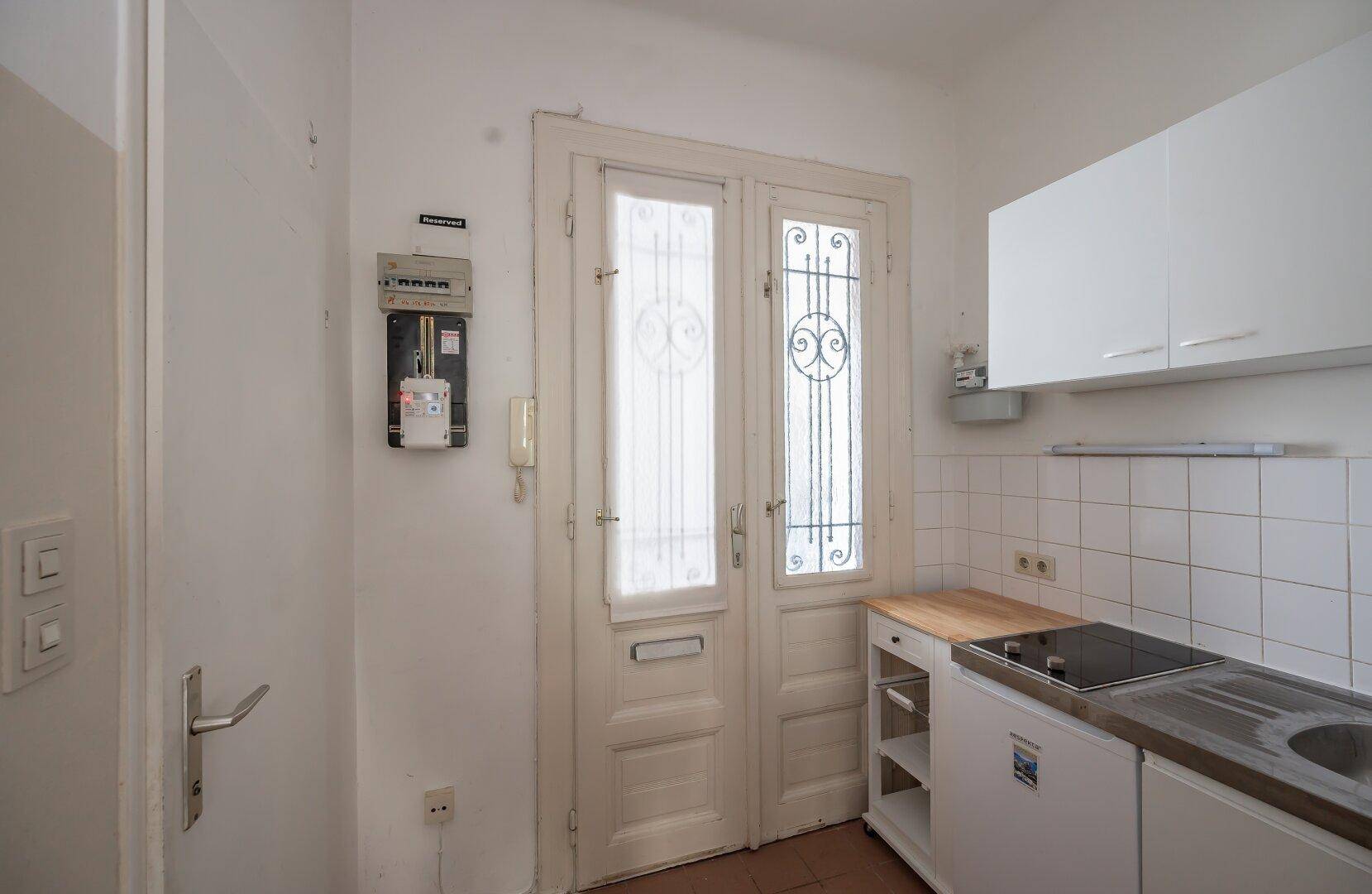 Küchenzeile mit Fenster und einfacher Ausstattung, inklusive Kochfeld und Spülbecken.