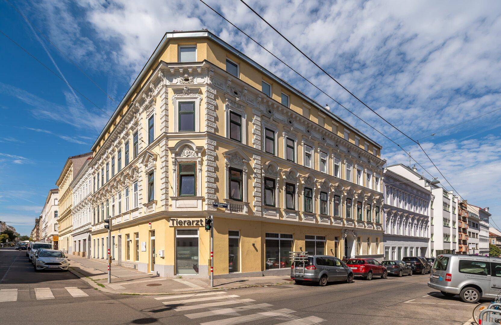 Historisches Eckgebäude mit reich verzierter Fassade und Geschäften im Erdgeschoss in der Stadt.