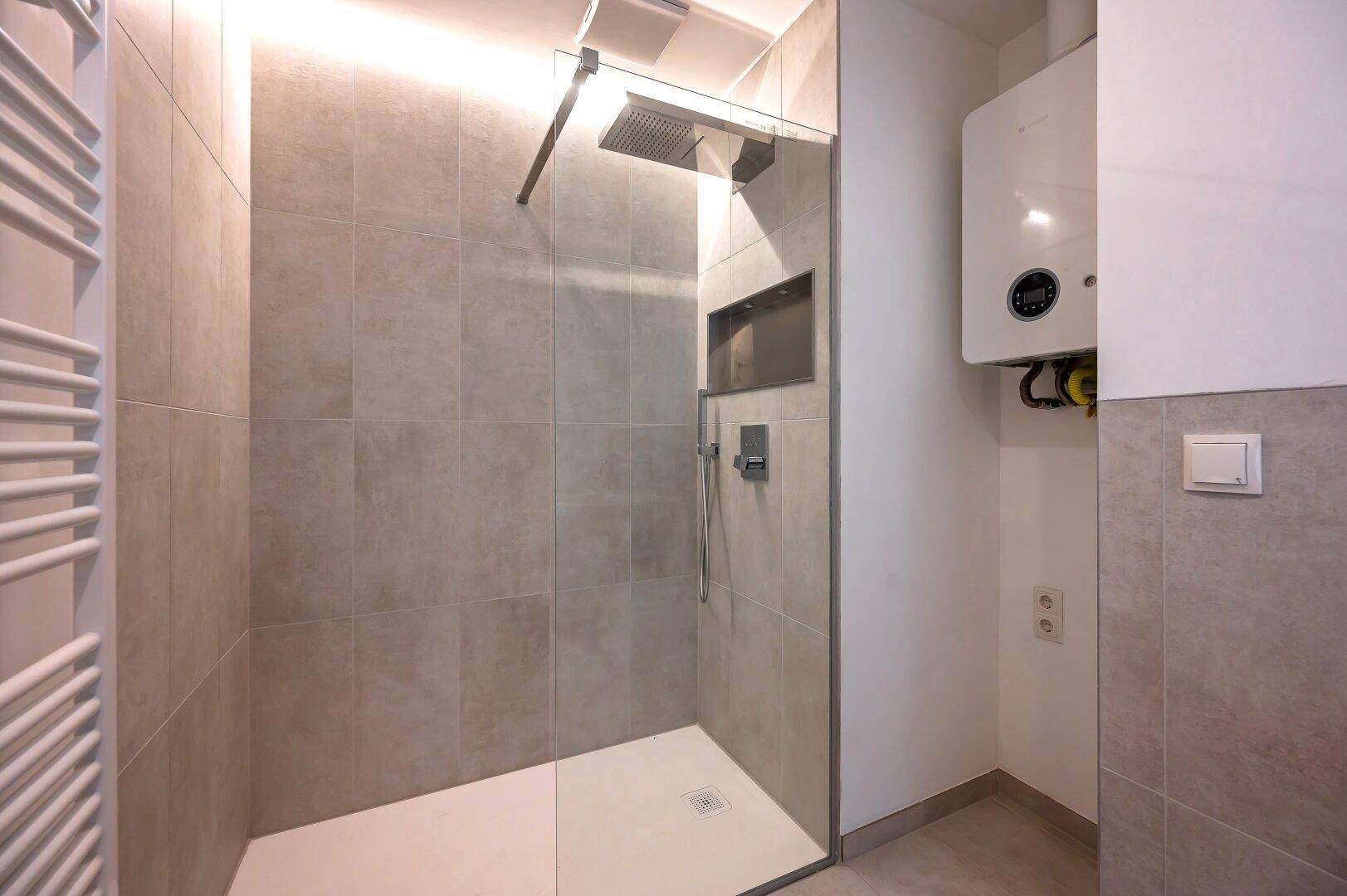 Geräumige begehbare Dusche mit Regenduschkopf und integriertem Warmwasserbereiter im Badezimmer.