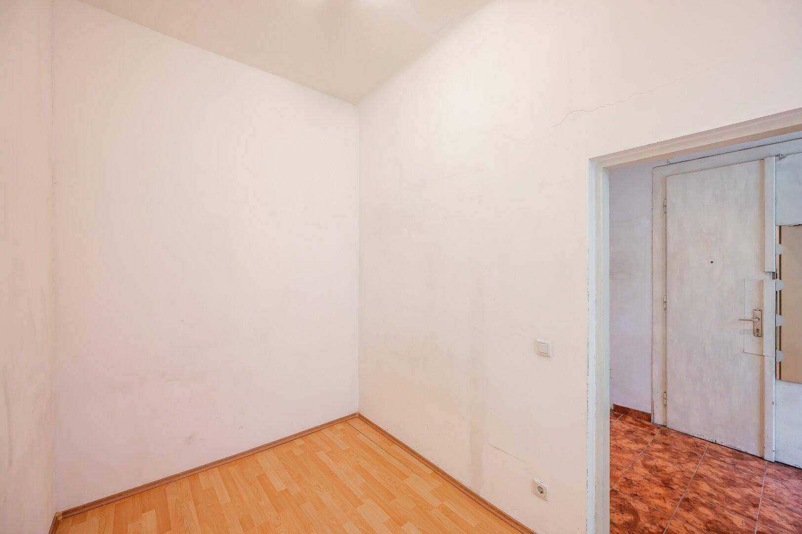 Kleines Zimmer mit hellem Parkettboden und weißen Wänden, ideal als Schlaf- oder Arbeitszimmer.