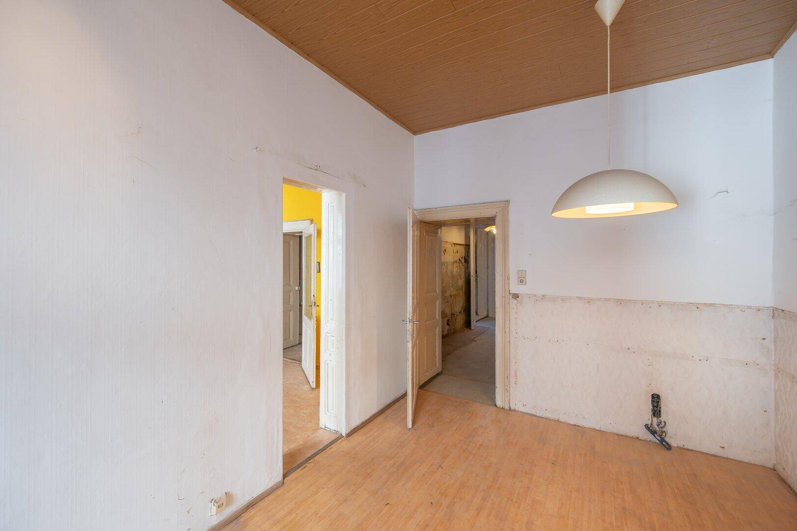 Raum mit Holzdecke und vorbereiteten Anschlüssen für eine Küche, bereit zur individuellen Gestaltung.