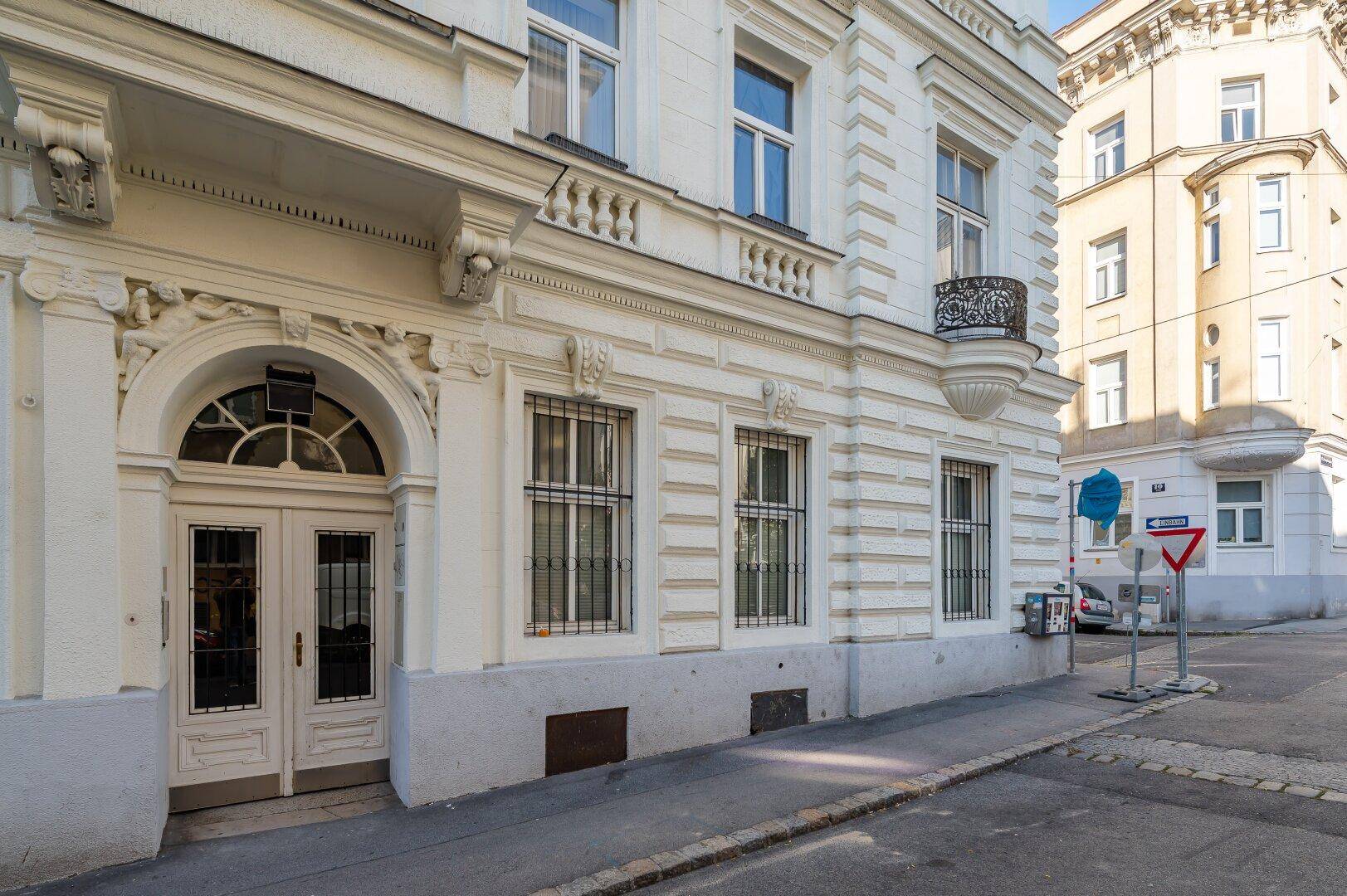 Elegante Altbaufassade mit Stuckverzierungen und kleinem Balkon in einer städtischen Umgebung.