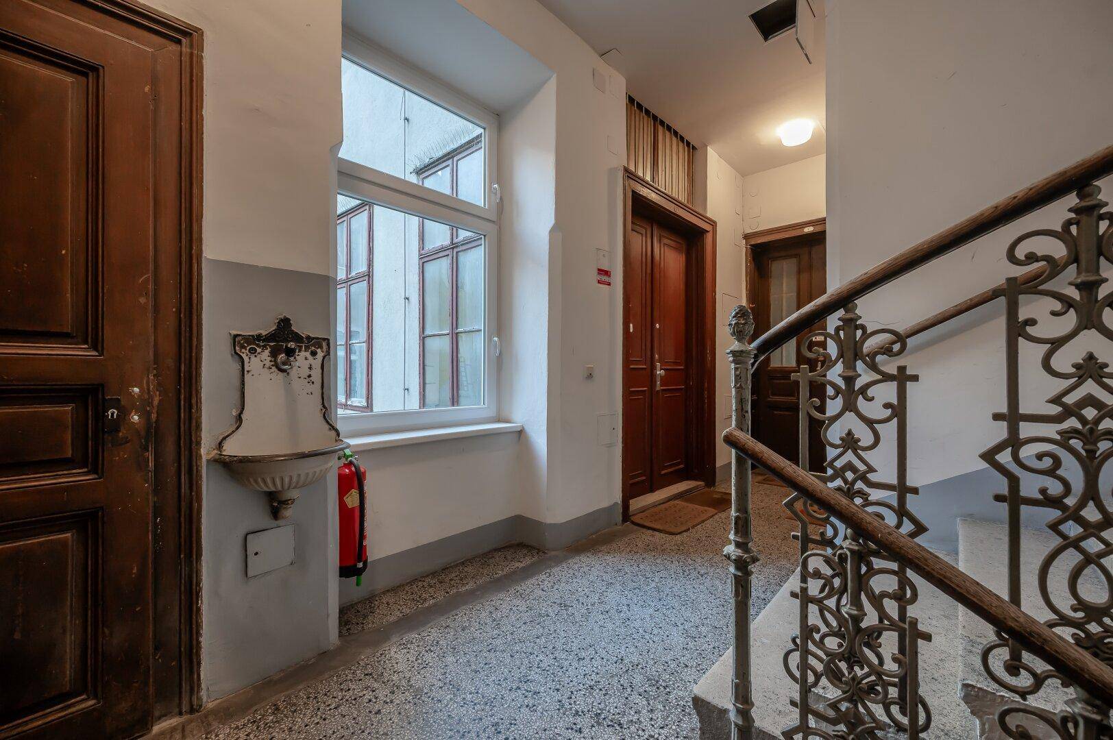 Historisches Treppenhaus mit schmiedeeisernem Geländer und Terrazzoboden, in einem Altbau.