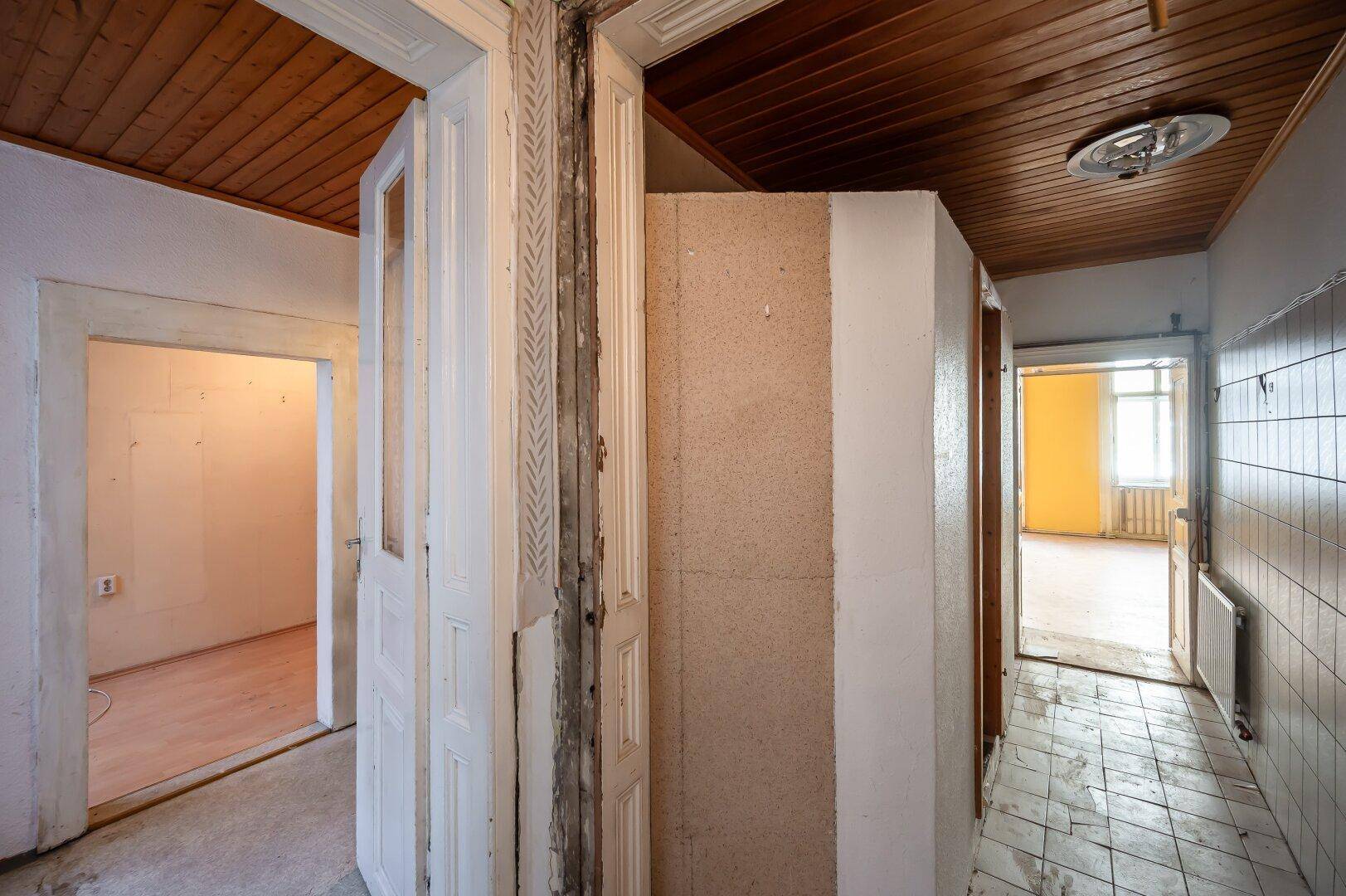 Langer Flur mit Holzdecke und mehreren Türen, der den Zugang zu verschiedenen Räumen ermöglicht.