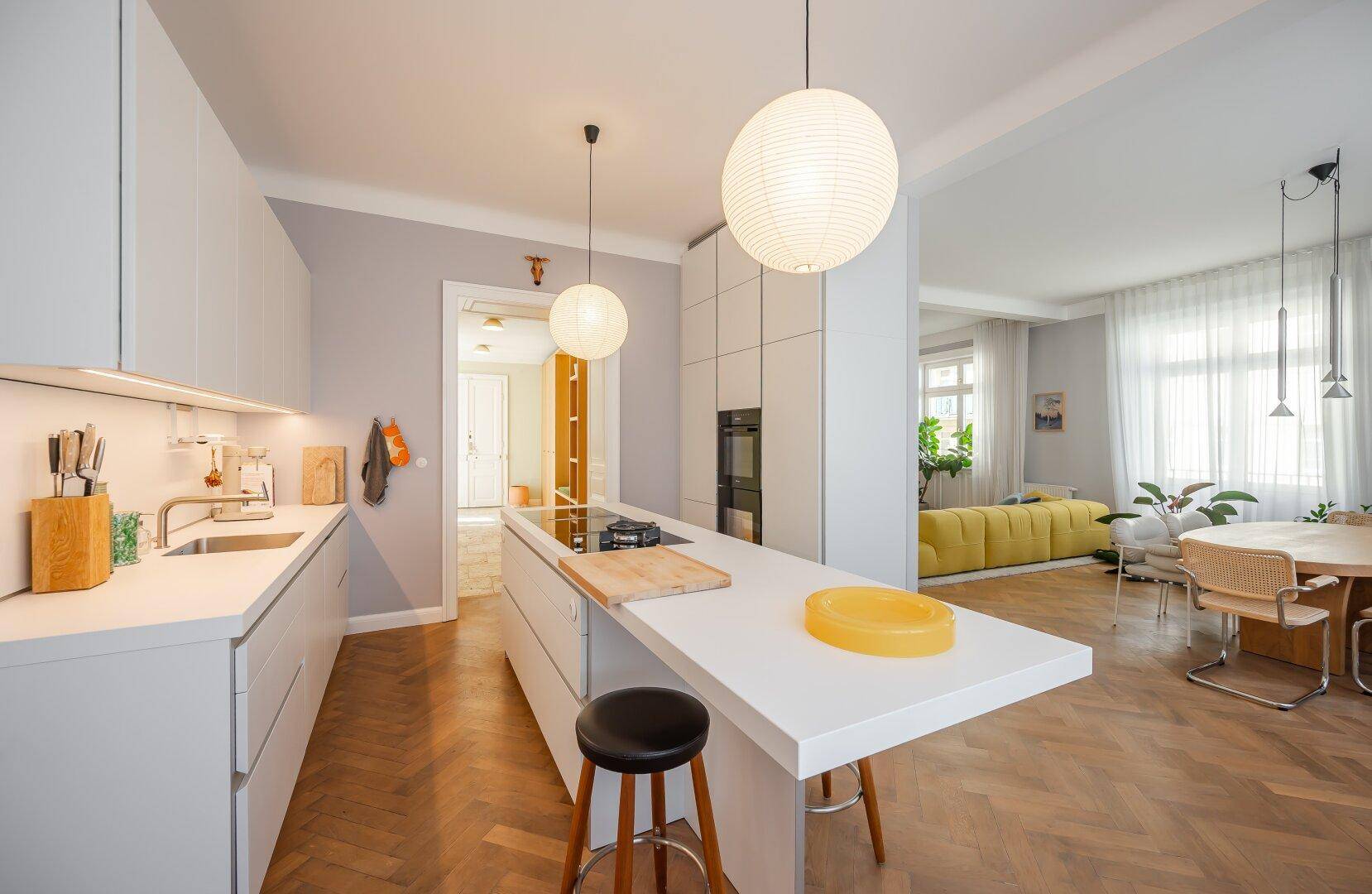 Helle, moderne Küche mit weißer Kochinsel, integrierten Geräten und Parkettboden.