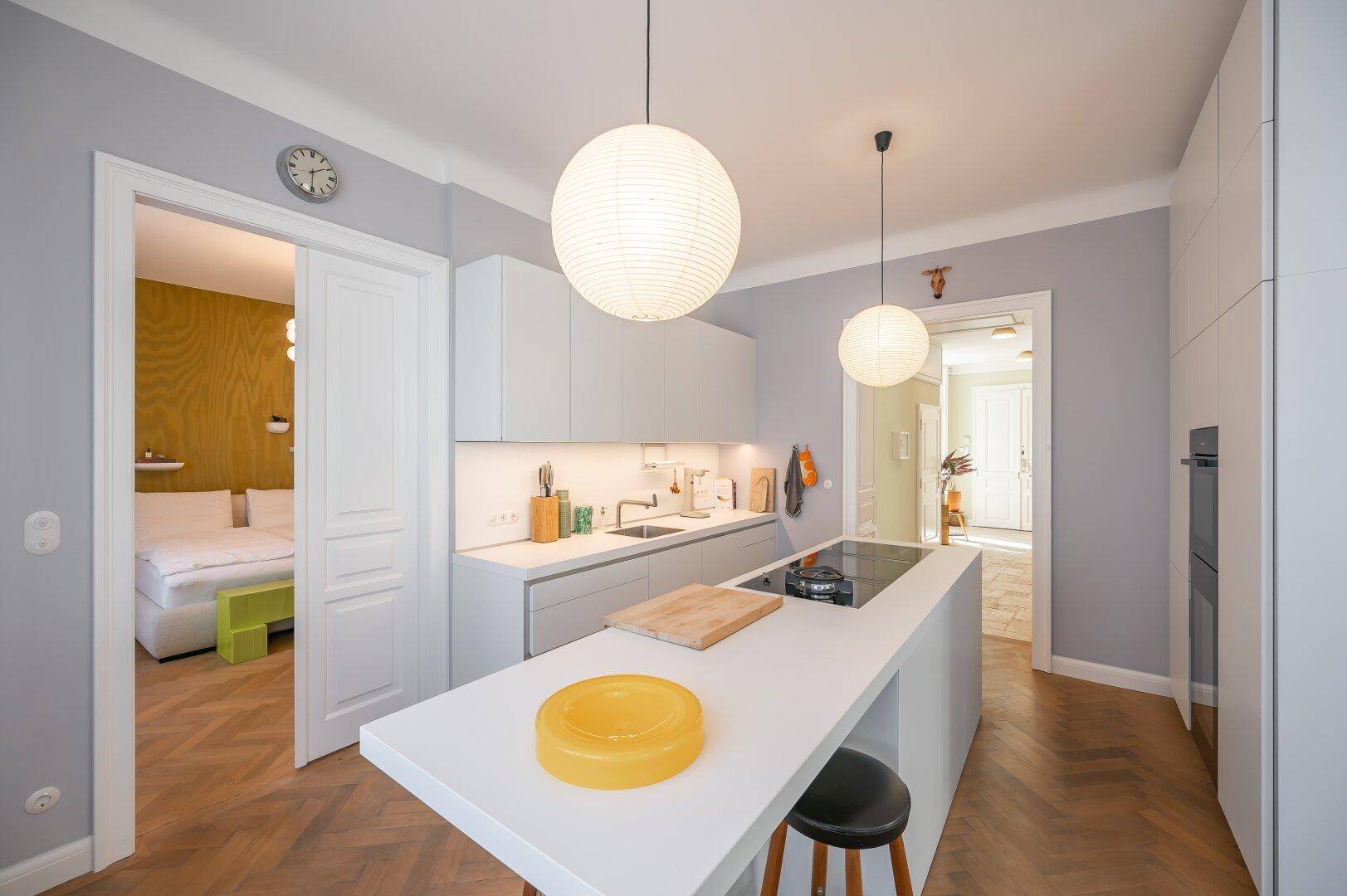 Funktionale, moderne Küche mit Kochinsel und Blick in das angrenzende Schlafzimmer.