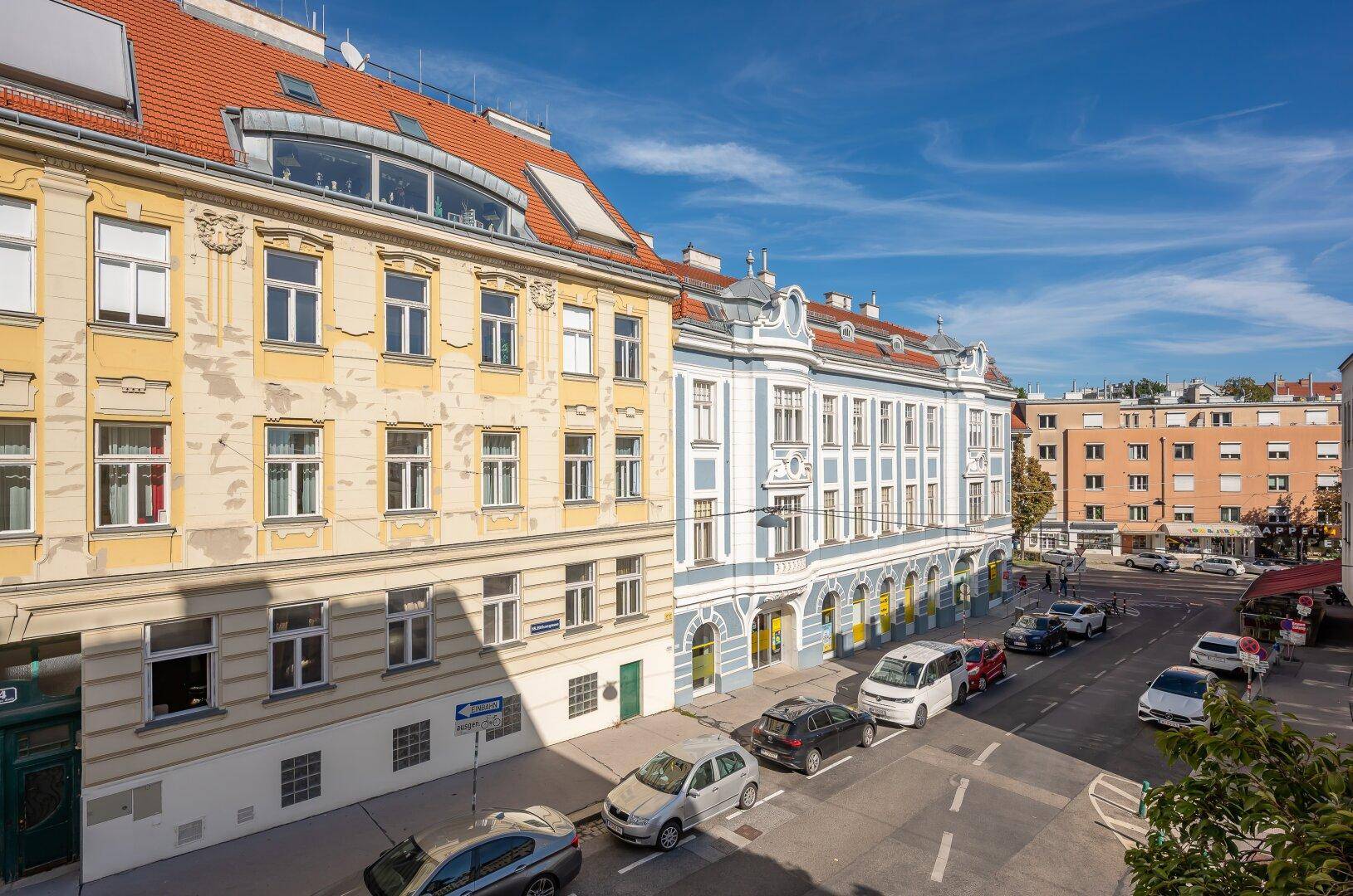 Panoramablick auf eine städtische Straße mit einer Reihe von Gebäuden unter blauem Himmel.