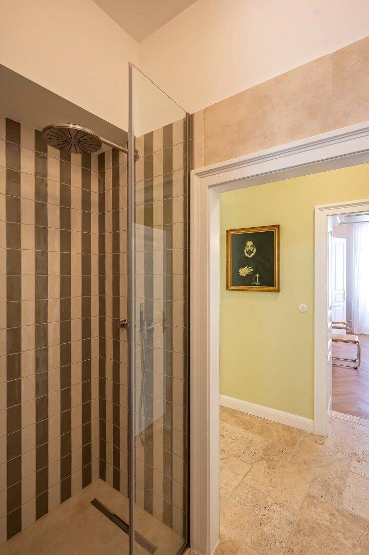 Moderne Dusche mit gestreiften Fliesen und Regendusche, angrenzend an den Flur.