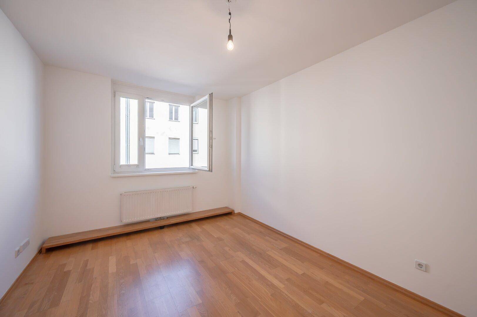 Helles Zimmer mit Parkettboden und Fensterbank, ideal als Schlaf- oder Arbeitszimmer nutzbar.