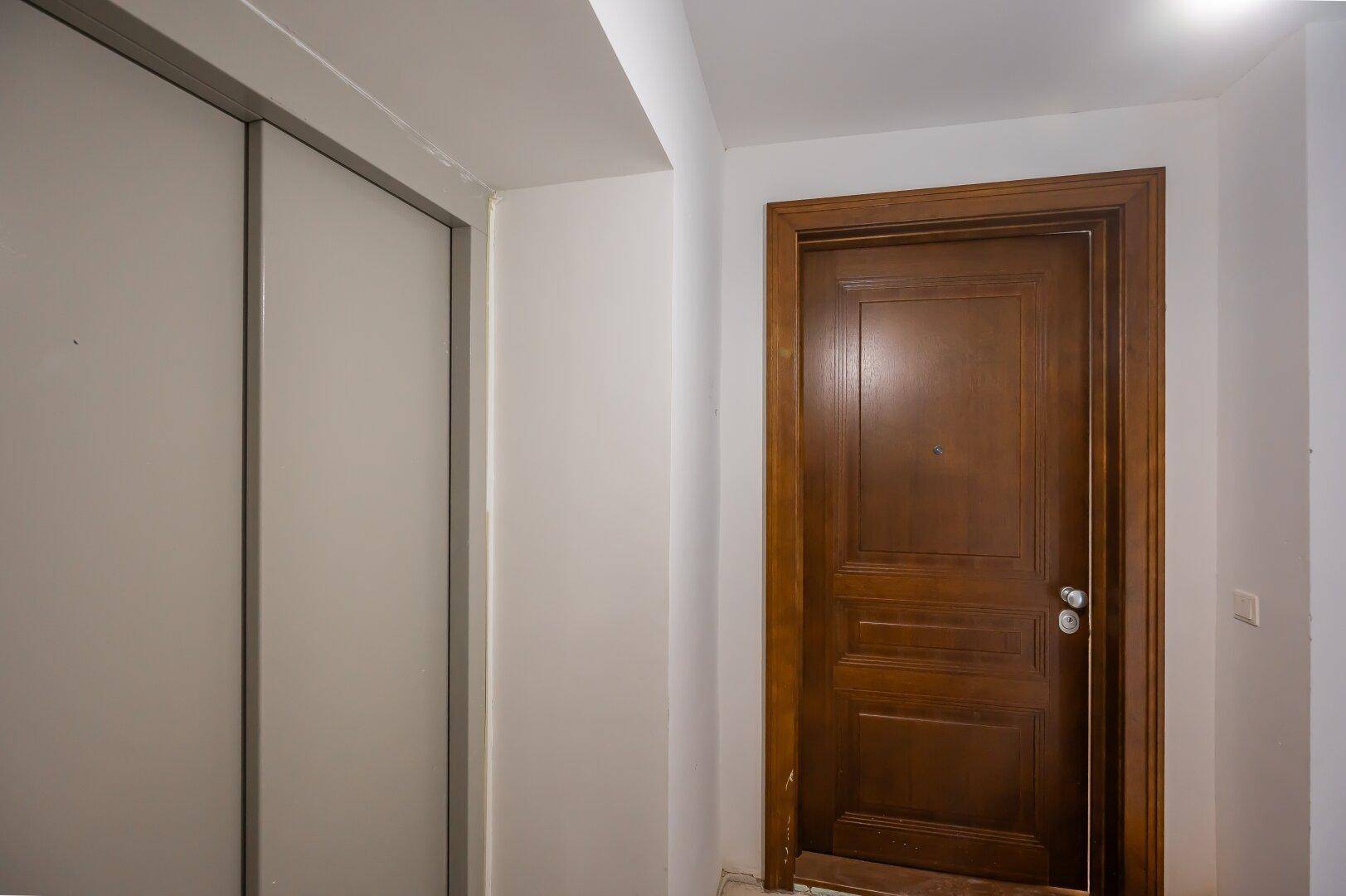 Flur mit einer Holztür und einem praktischen Einbauschrank mit Schiebetüren.