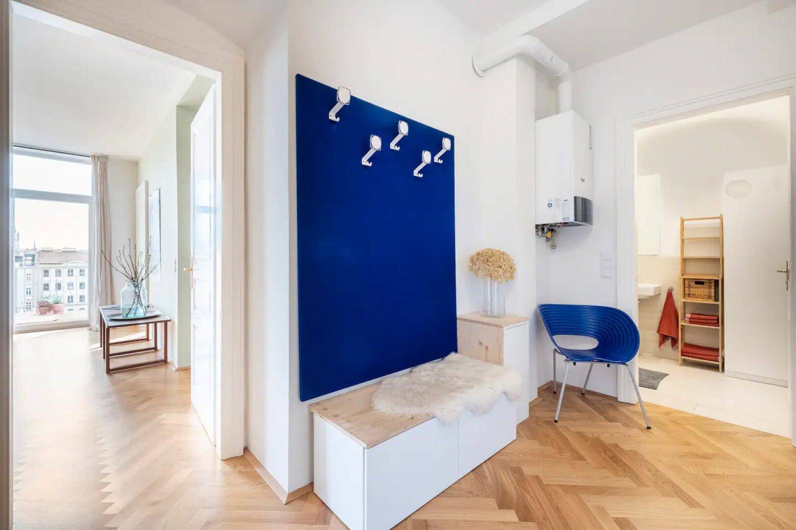 Heller Flur mit Fischgrätparkett, blauer Wandverkleidung und praktischer Garderobenbank.