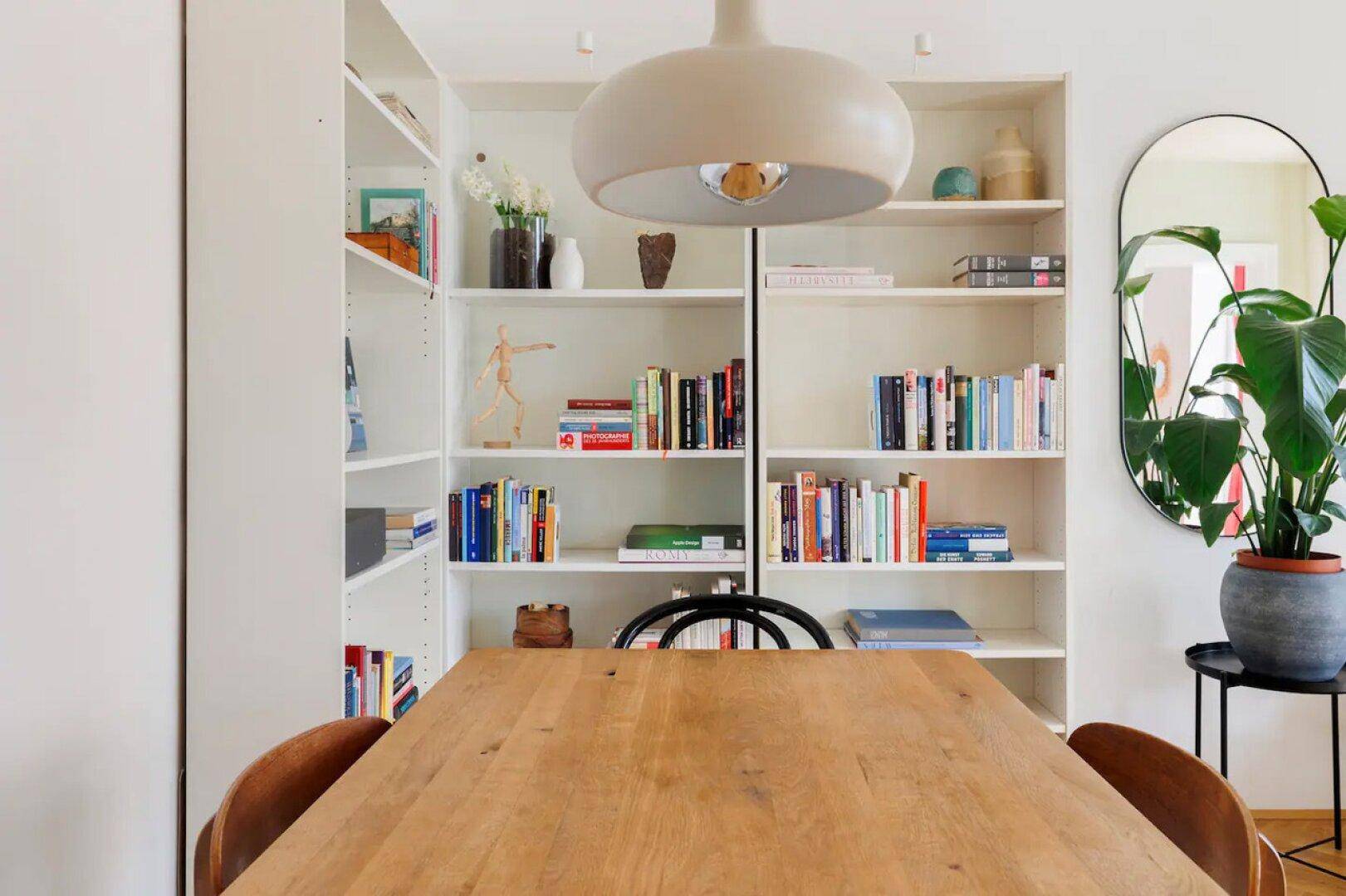 Essbereich mit Holztisch, Bücherregal und moderner Pendelleuchte, schafft eine gemütliche Atmosphäre.