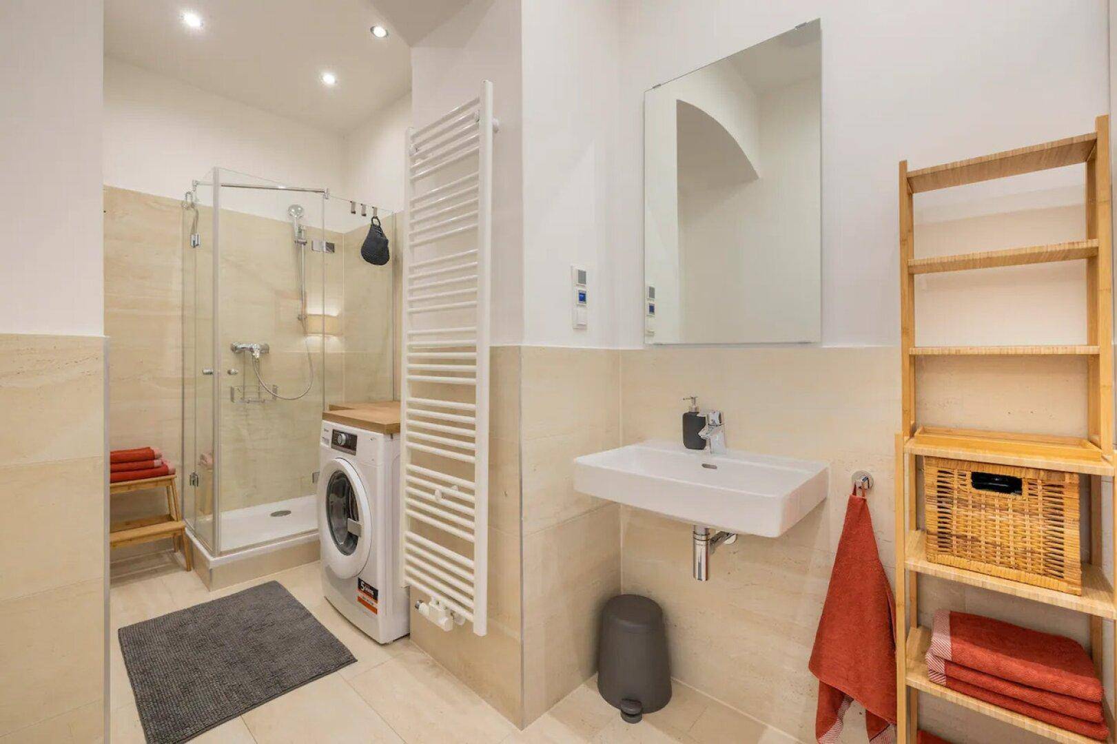 Modernes Badezimmer mit Dusche, Waschmaschine und beheiztem Handtuchhalter, funktional und hell.