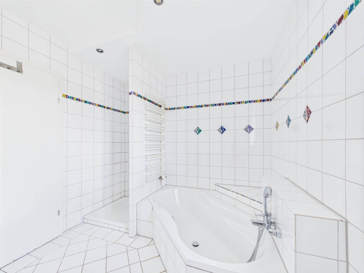 Modernes Badezimmer mit Badewanne, Dusche und beheiztem Handtuchhalter.