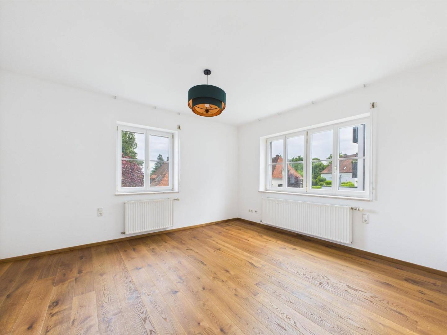 Geräumiges Schlafzimmer mit Holzboden und zwei großen Fenstern.