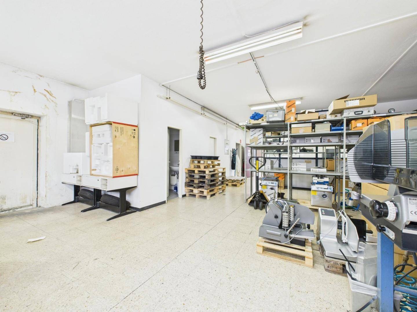 Geräumiger Lagerbereich mit verschiedenen Geräten, Paletten und Regalen für industrielle Nutzung oder Archivierung.