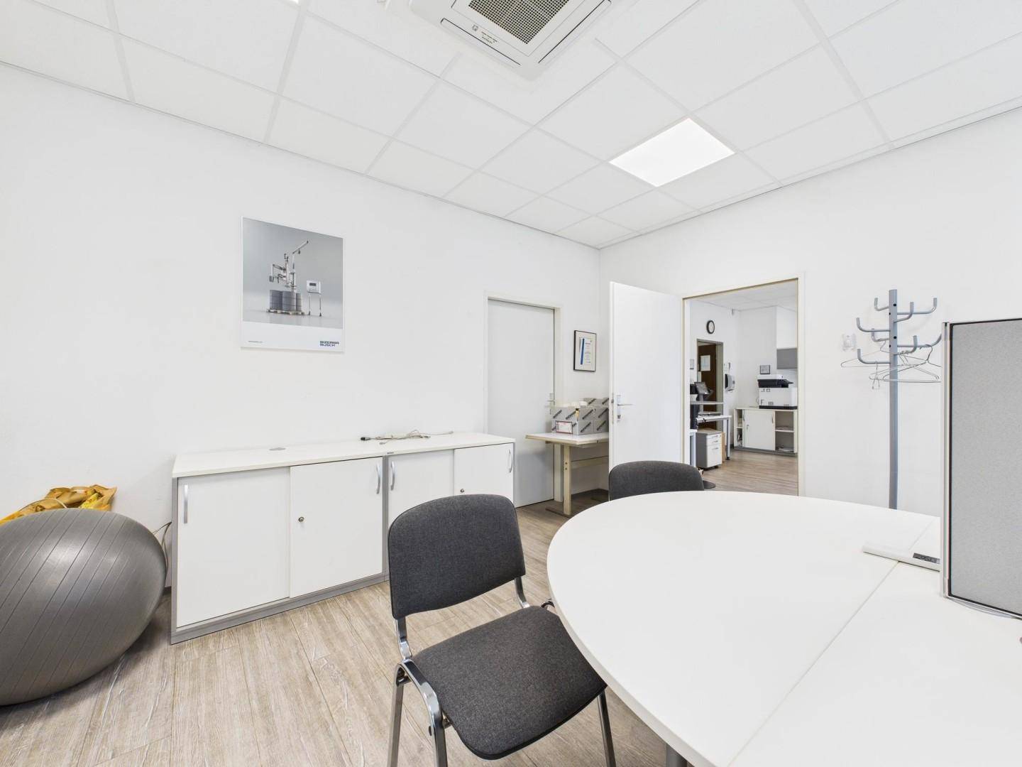 Heller Büroraum mit Schreibtisch, Stühlen und praktischen Aufbewahrungsschränken, ideal für konzentriertes Arbeiten.
