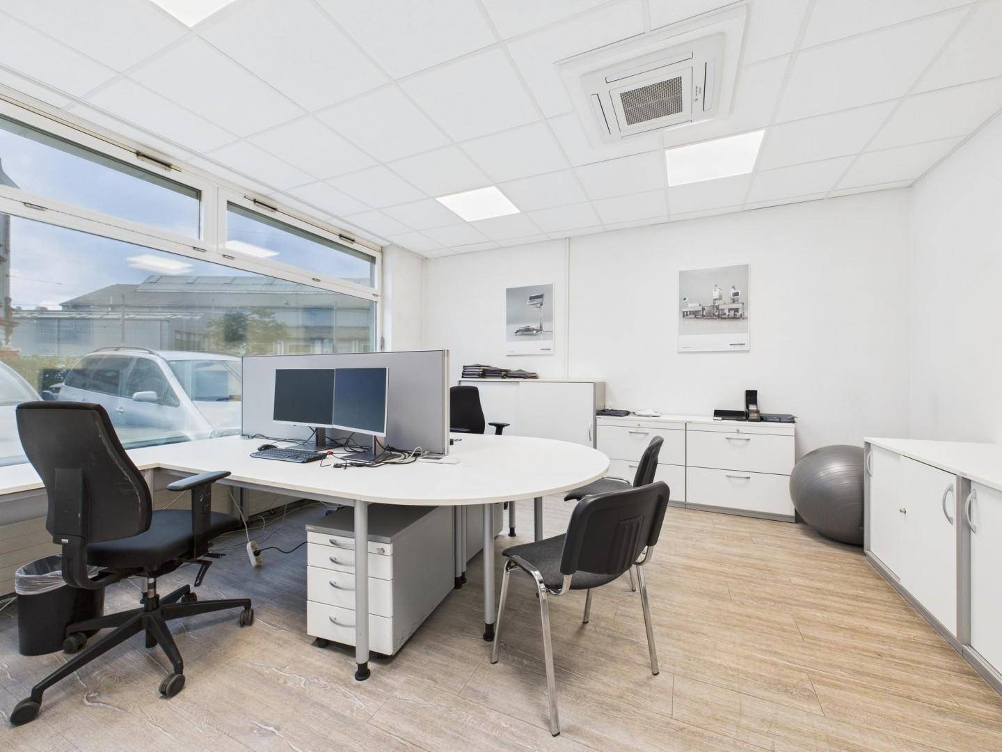 Modernes Büro mit großem Schreibtisch, ergonomischen Stühlen und weitem Blick durch die Fenster.