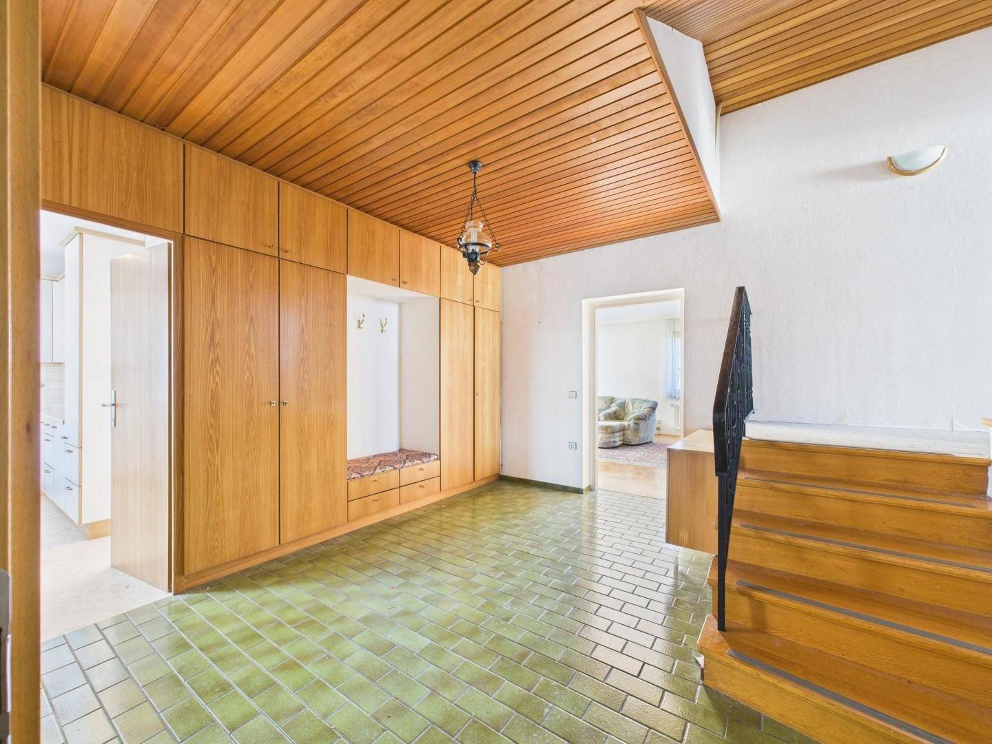 Eingangsbereich mit Holzdecke, grünen Fliesen und integrierten Holzschränken.
