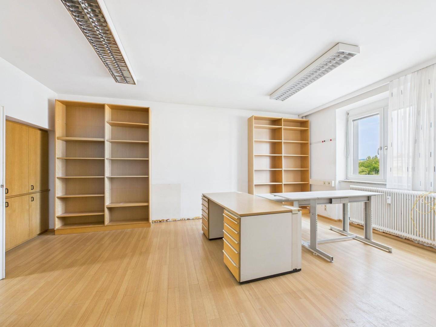 Helles Büro mit Laminatboden, Regalen und Schreibtischen, bereit für die Nutzung.