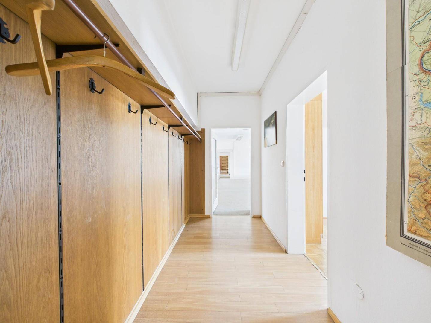 Langer Flur mit Holzverkleidung und Garderobe, der zu weiteren Räumen im Gebäude führt.