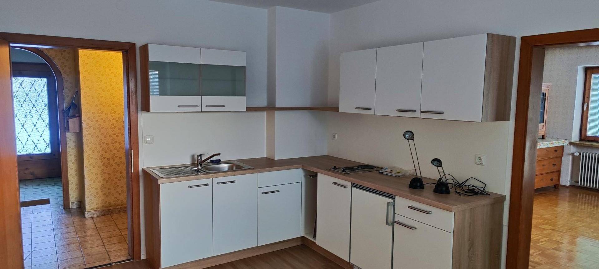 Moderne Einbauküche mit weißen Schränken, Holztheke und Blick in den Flur.