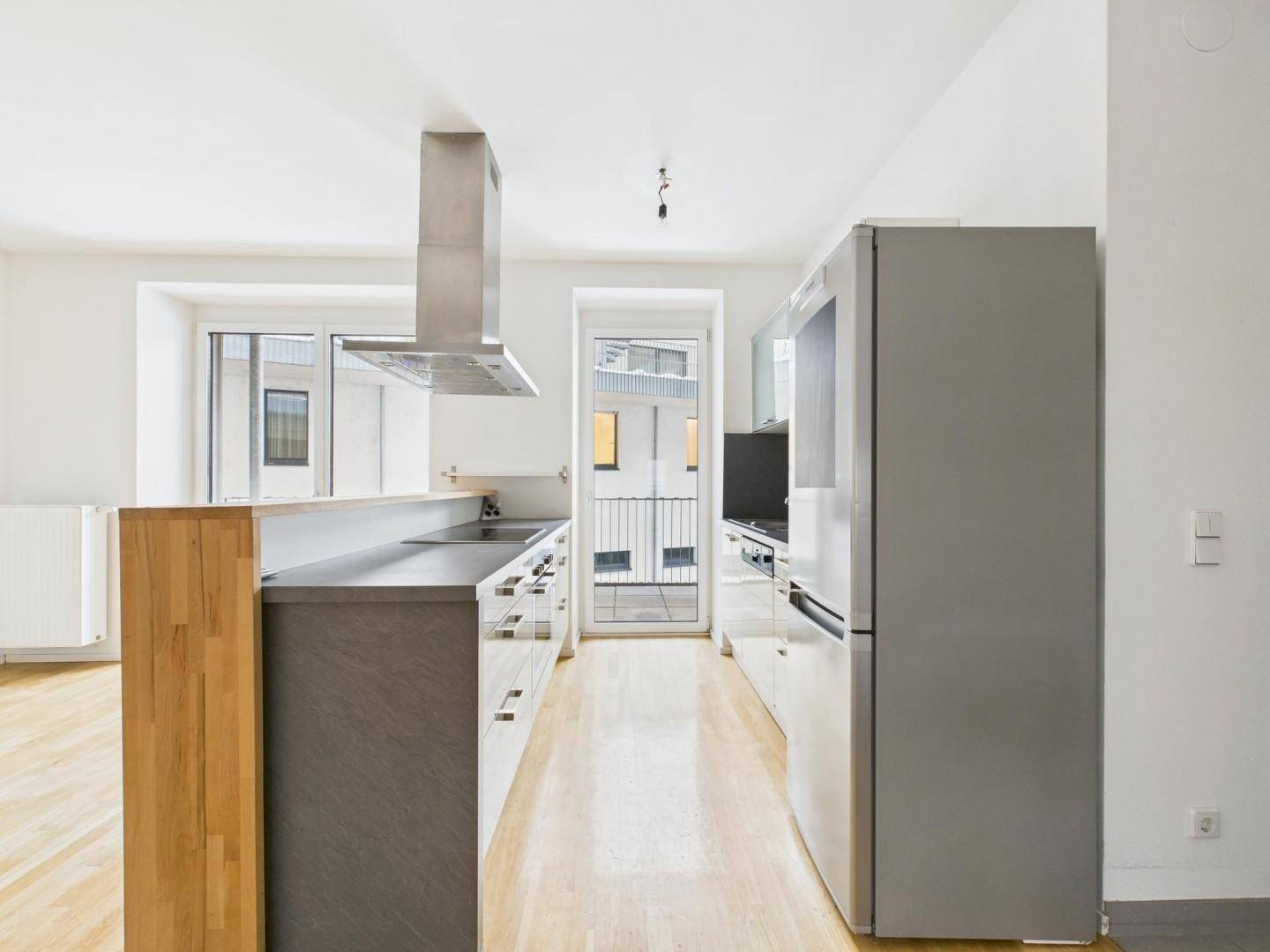 Moderne Einbauküche mit Edelstahlgeräten und Zugang zu einem französischen Balkon.
