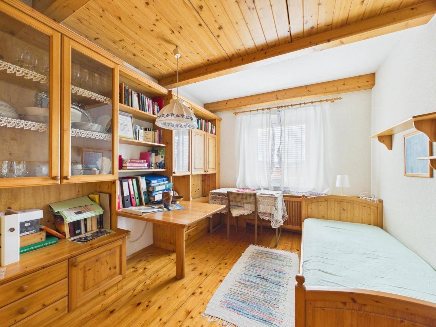 Schlafzimmer mit Holzboden, Holzdecke, Einbauschränken und einem Einzelbett.