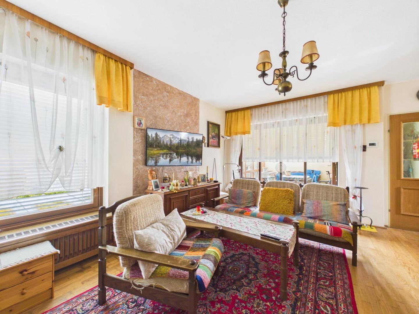 Gemütliches Wohnzimmer mit traditionellen Sitzmöbeln, Holzboden und viel Tageslicht.