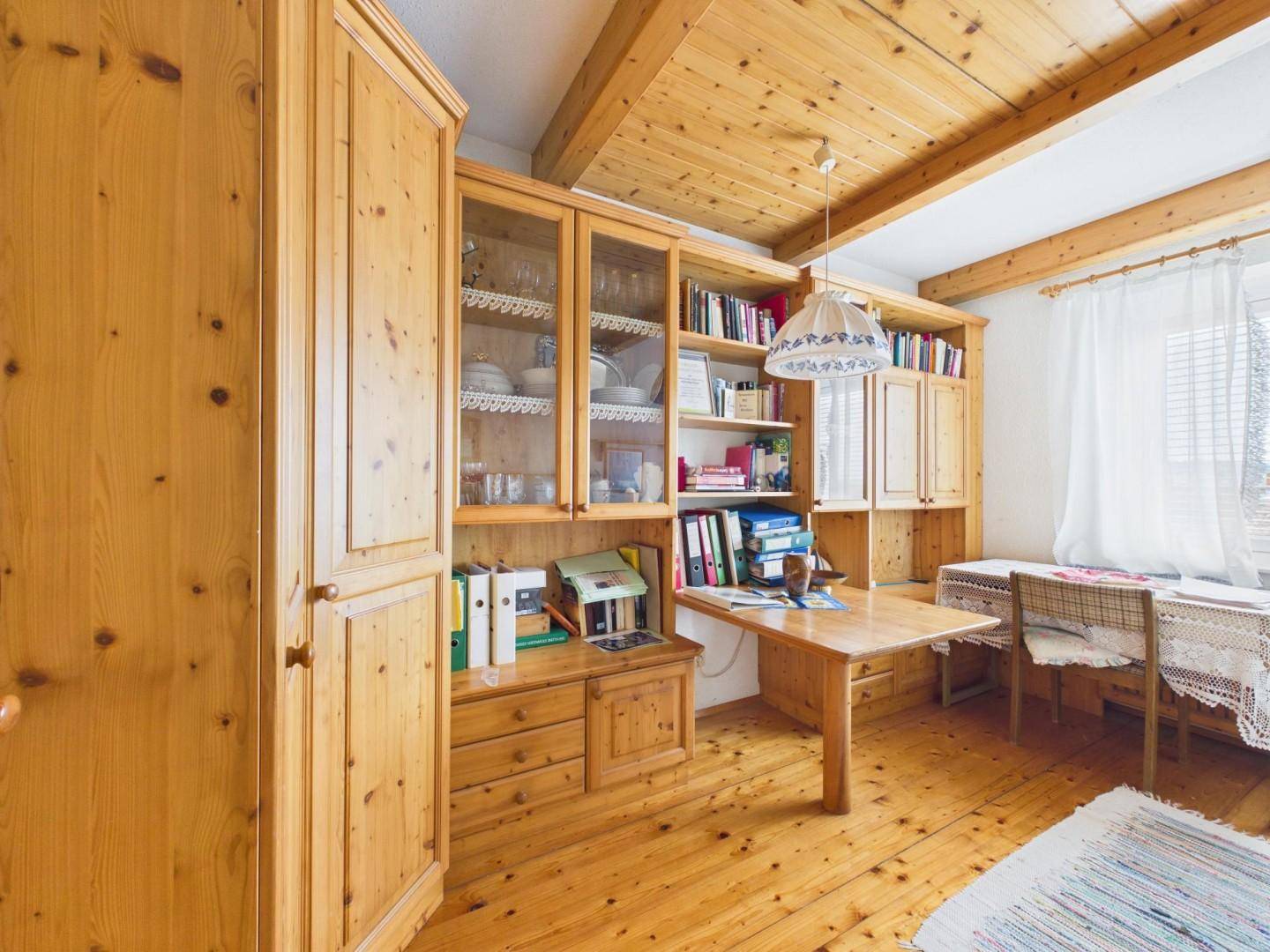 Zimmer mit maßgefertigten Holzschränken, Holzboden und einer sichtbaren Holzdecke.