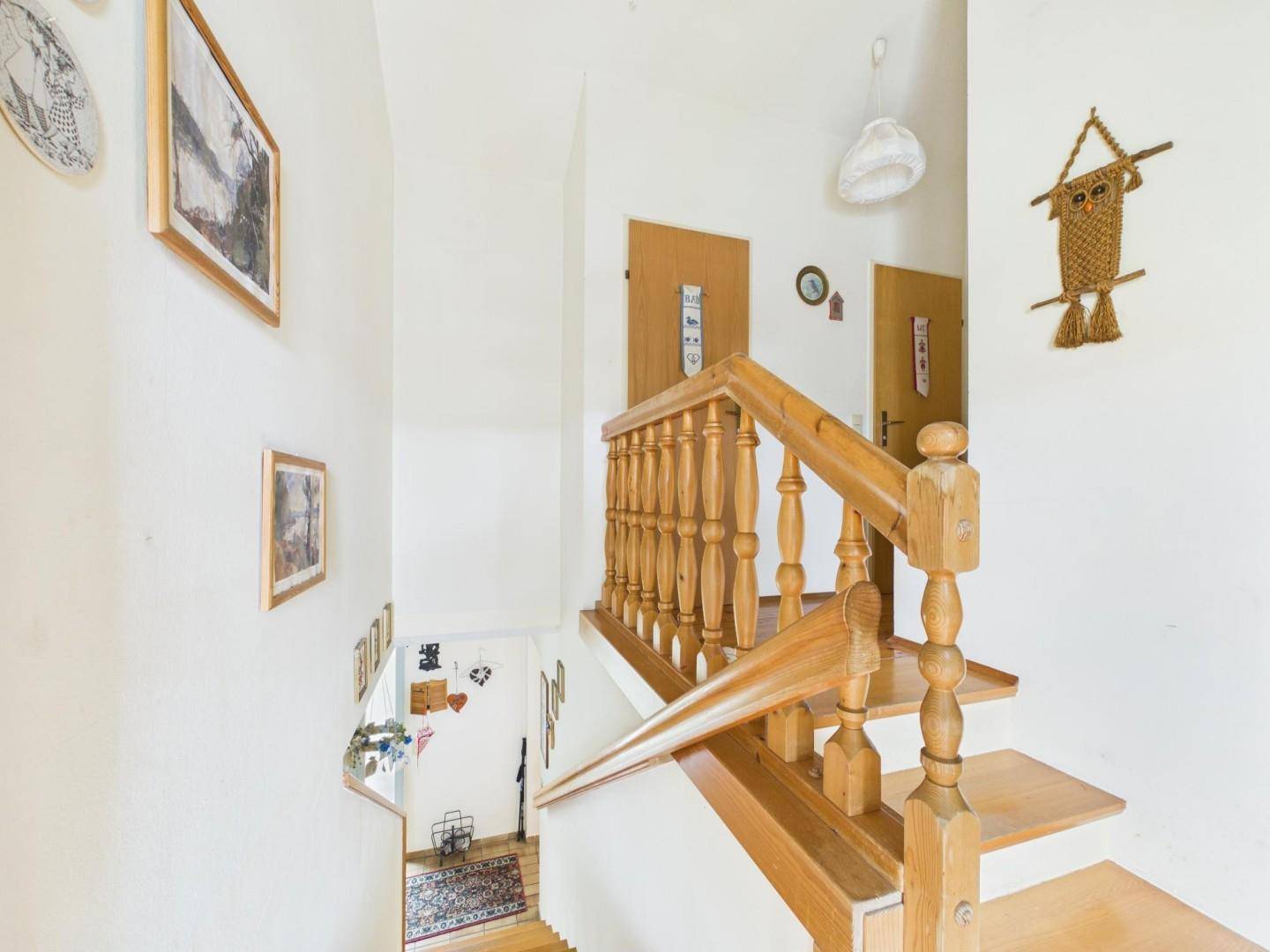 Holztreppe mit gedrechseltem Geländer, die verschiedene Ebenen des Hauses verbindet.
