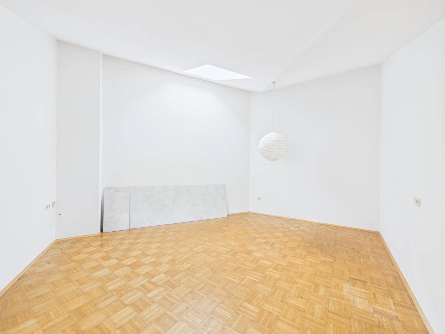 Heller Wohnraum mit Parkettboden, Oberlicht und moderner Deckenleuchte.