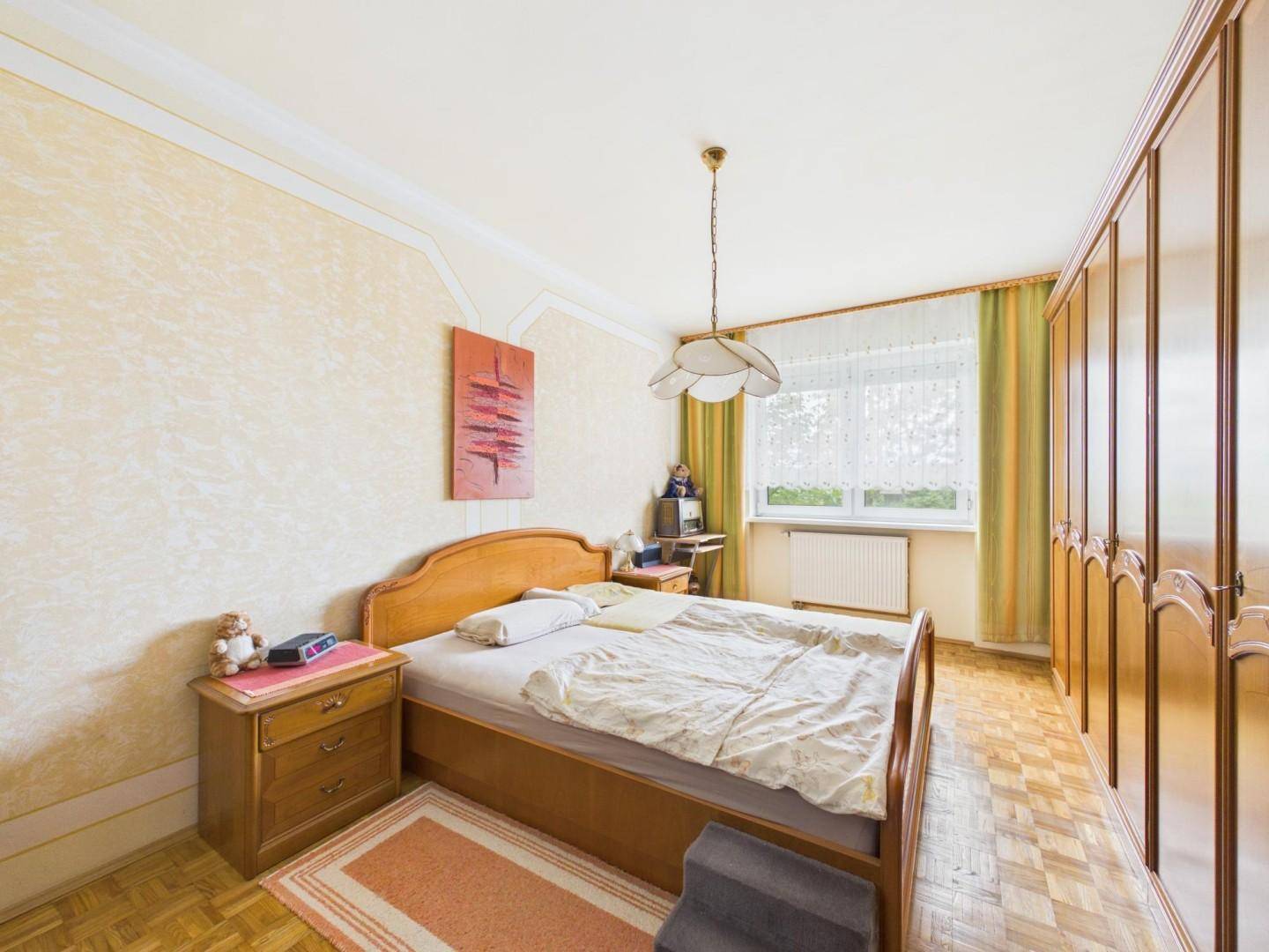 Gemütliches Schlafzimmer mit klassischem Holzbett, großem Kleiderschrank und Parkettboden.