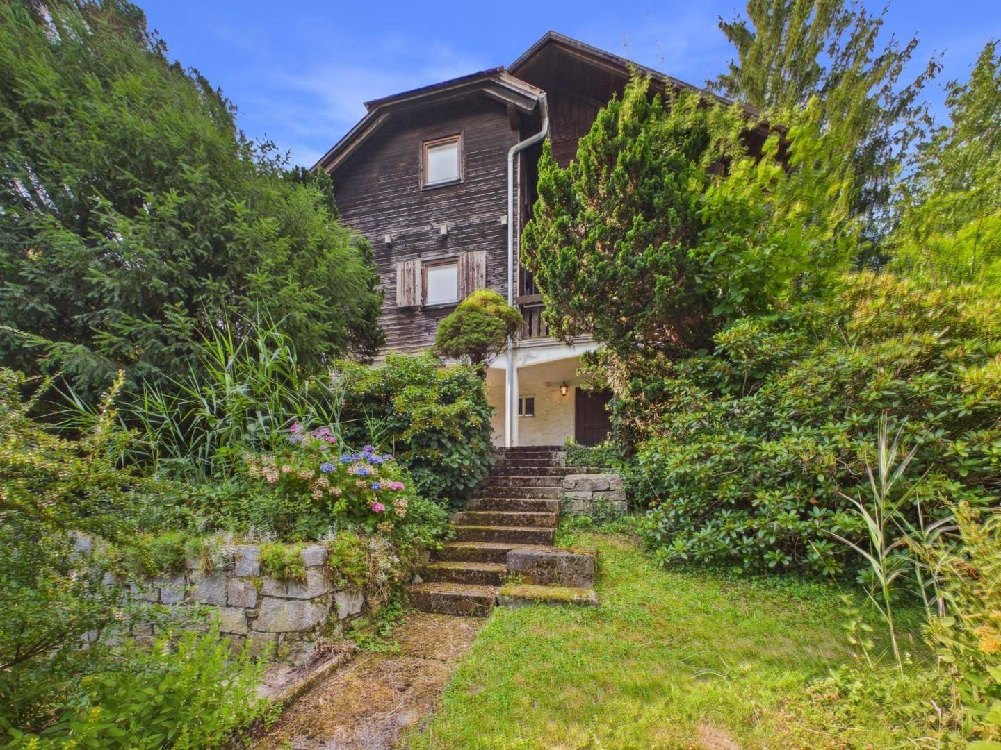 Traditionelles Holzhaus mit Steintreppe und umgebendem, gepflegtem Garten.