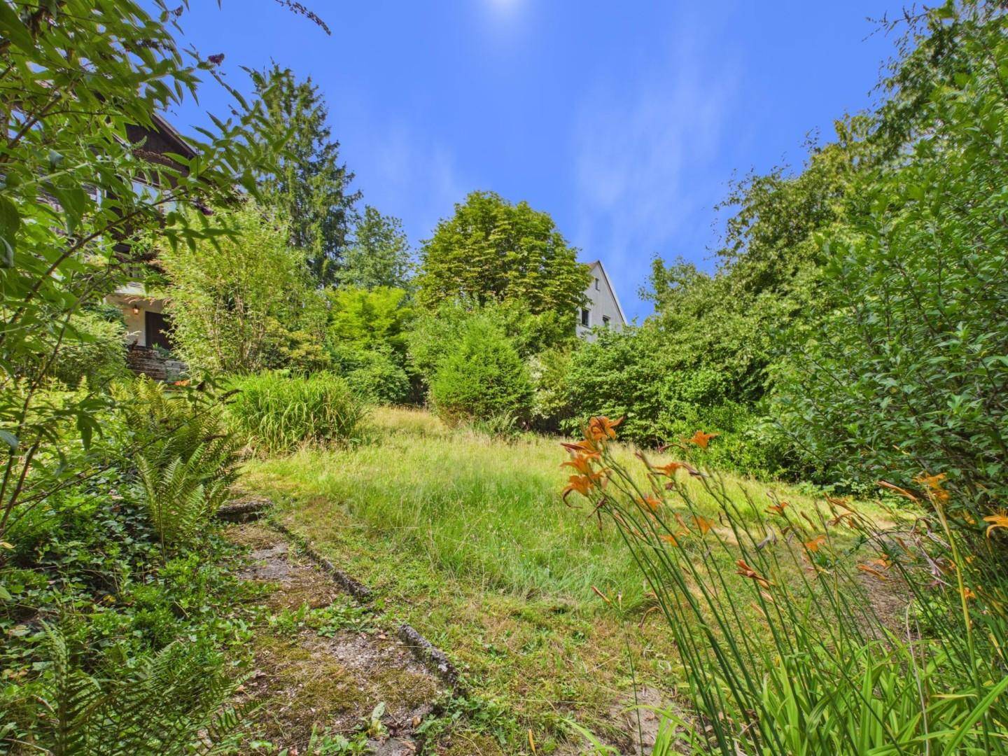 Hanglage im Garten mit üppiger Vegetation und Blick auf die umliegende Natur.