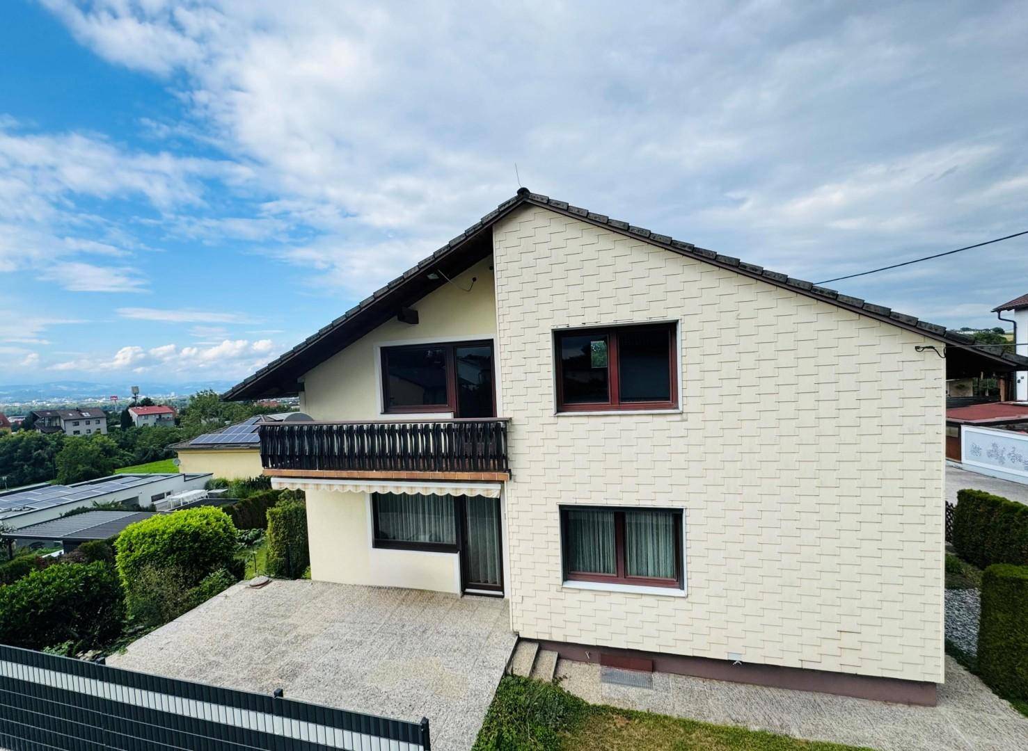 Gesamtansicht des Hauses von oben mit Balkon, Terrasse und umliegender Landschaft.