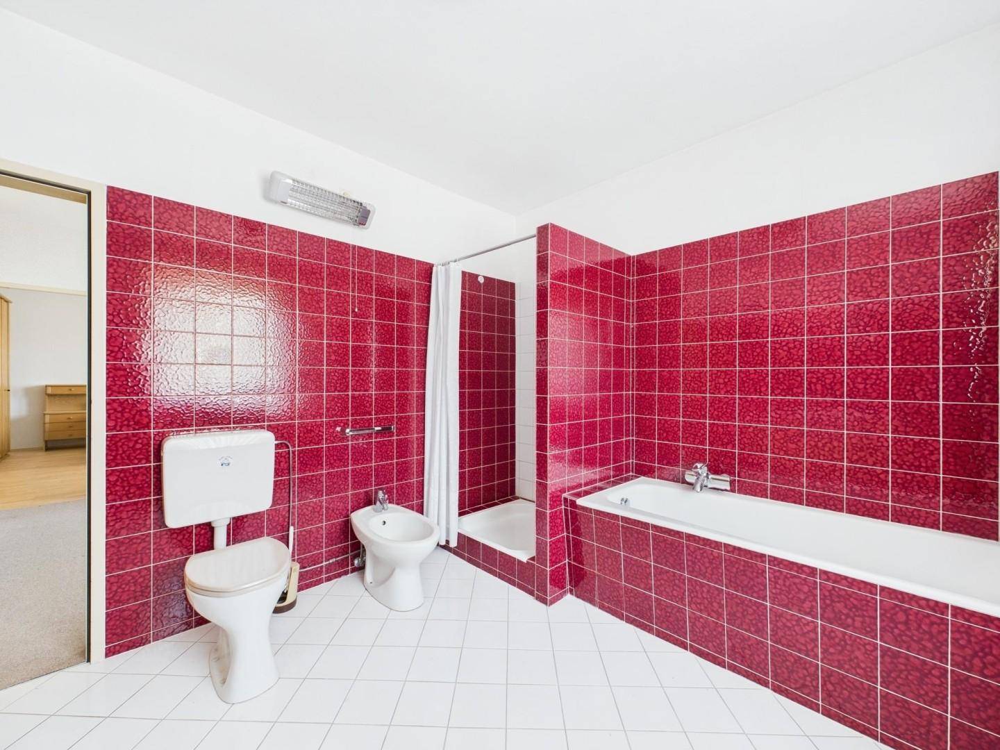 Badezimmer mit roten Fliesen, Badewanne, Dusche, WC und Bidet.