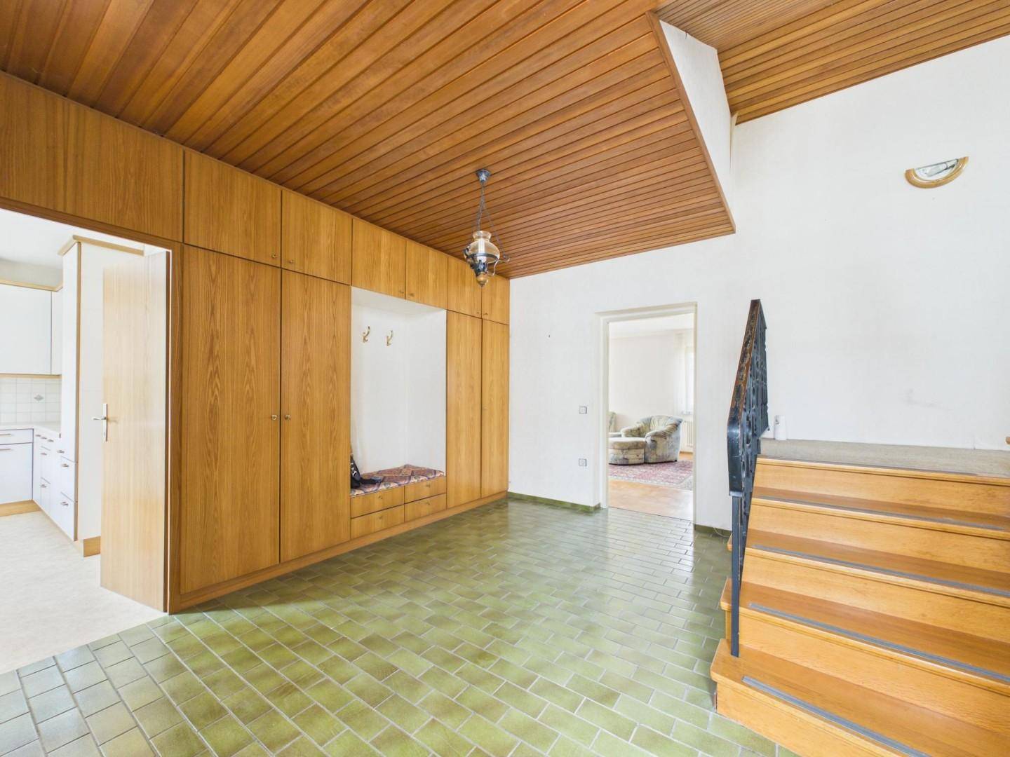 Eingangsbereich mit Holzvertäfelung, Einbauschränken und gefliestem Boden in Grün.