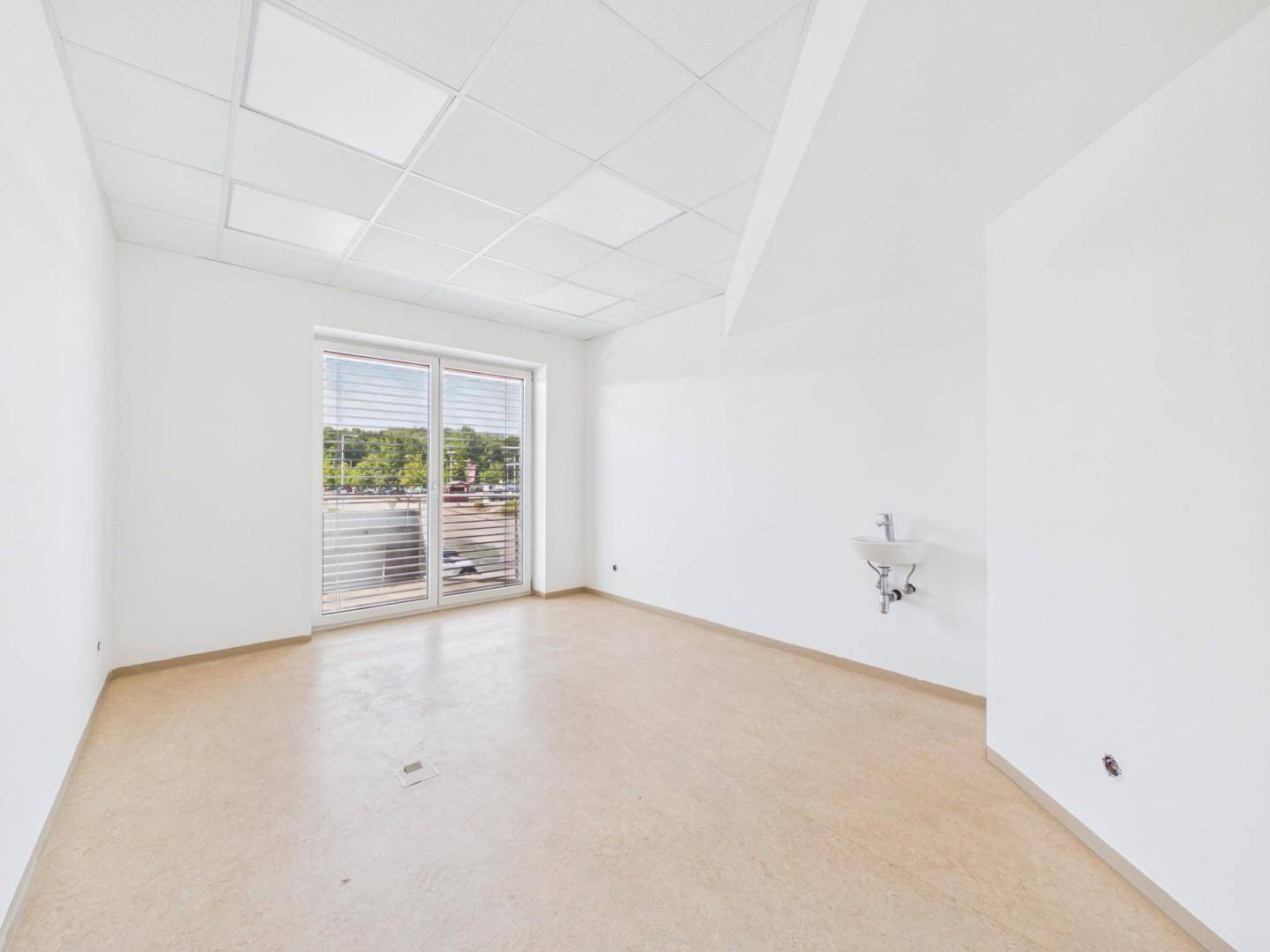 Heller Raum mit Fenster, hellem Boden und einem kleinen Waschbecken an der Wand, ideal für gewerbliche Nutzung.