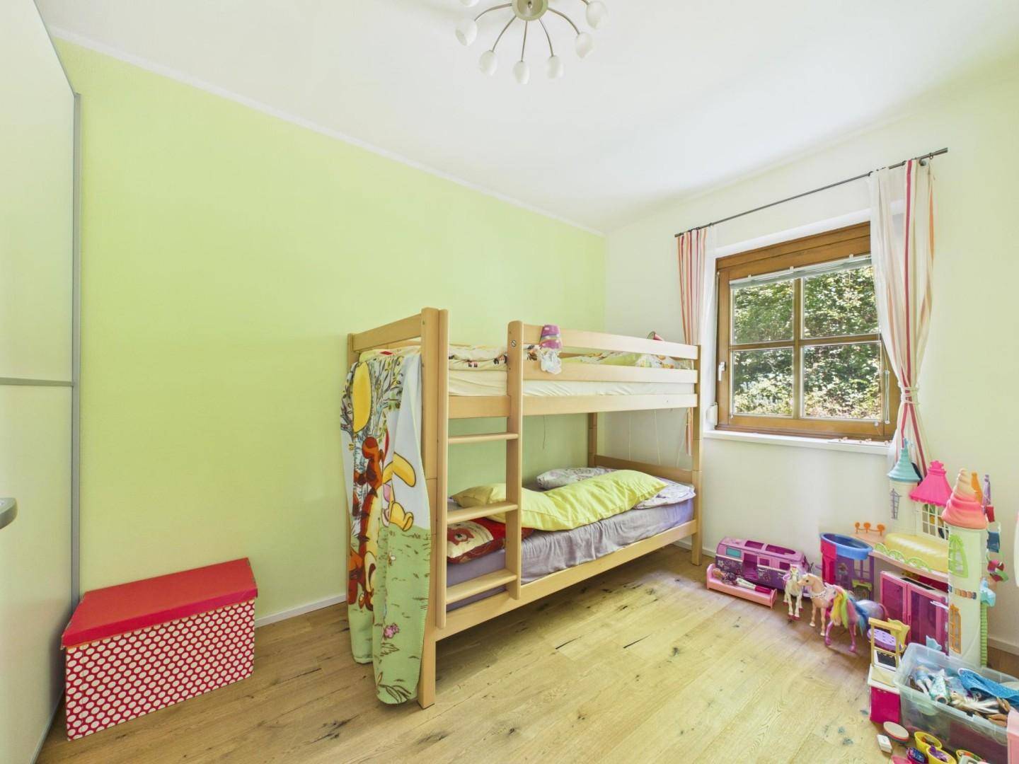 Kinderzimmer mit Etagenbett, Spielzeug und hellgrünen Wänden, ideal für Geschwister.